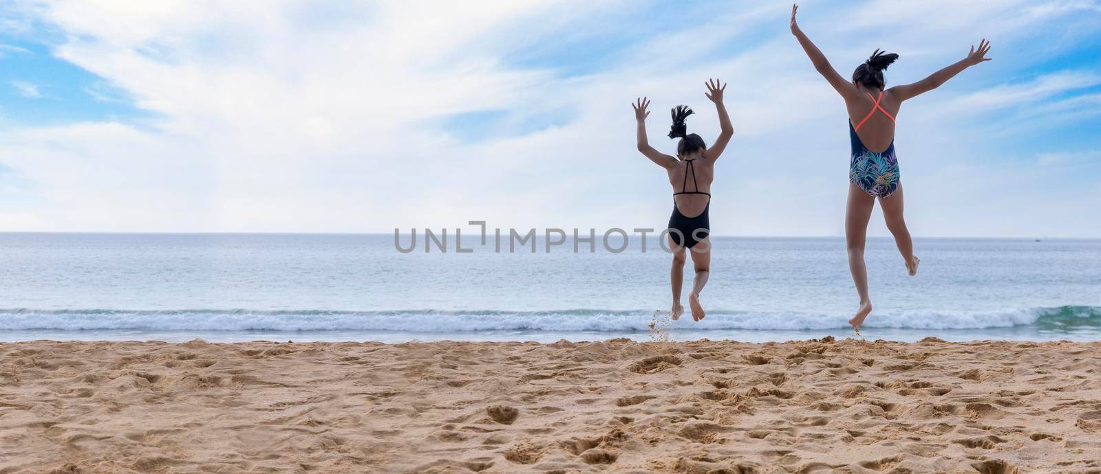 Motion movement happy two children wear swimwear running and jumping from beach to the sea. Happy family holiday summer concept. Two girl running to beach with copy space by Satrinekarn