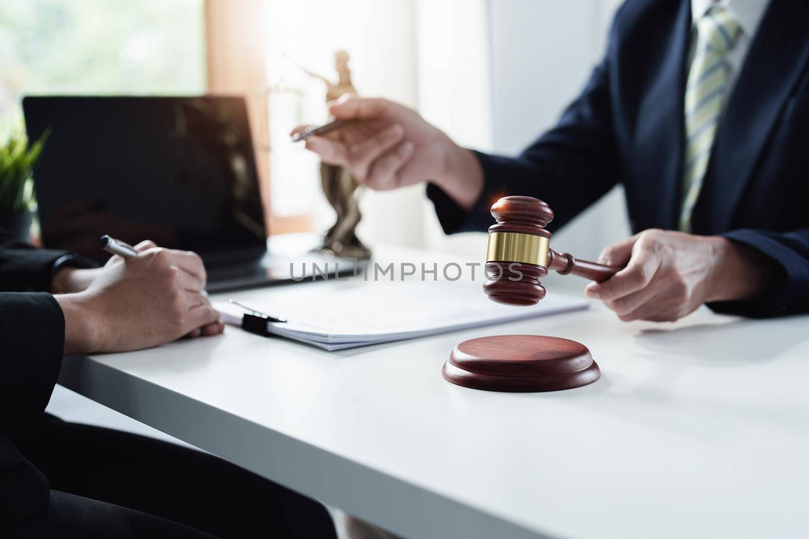 Focus at gavel, Attorney or Lawyer holding a pen is consulting with a client to explain the pattern of answering questions before going to court to decide a lawsuit. by Manastrong