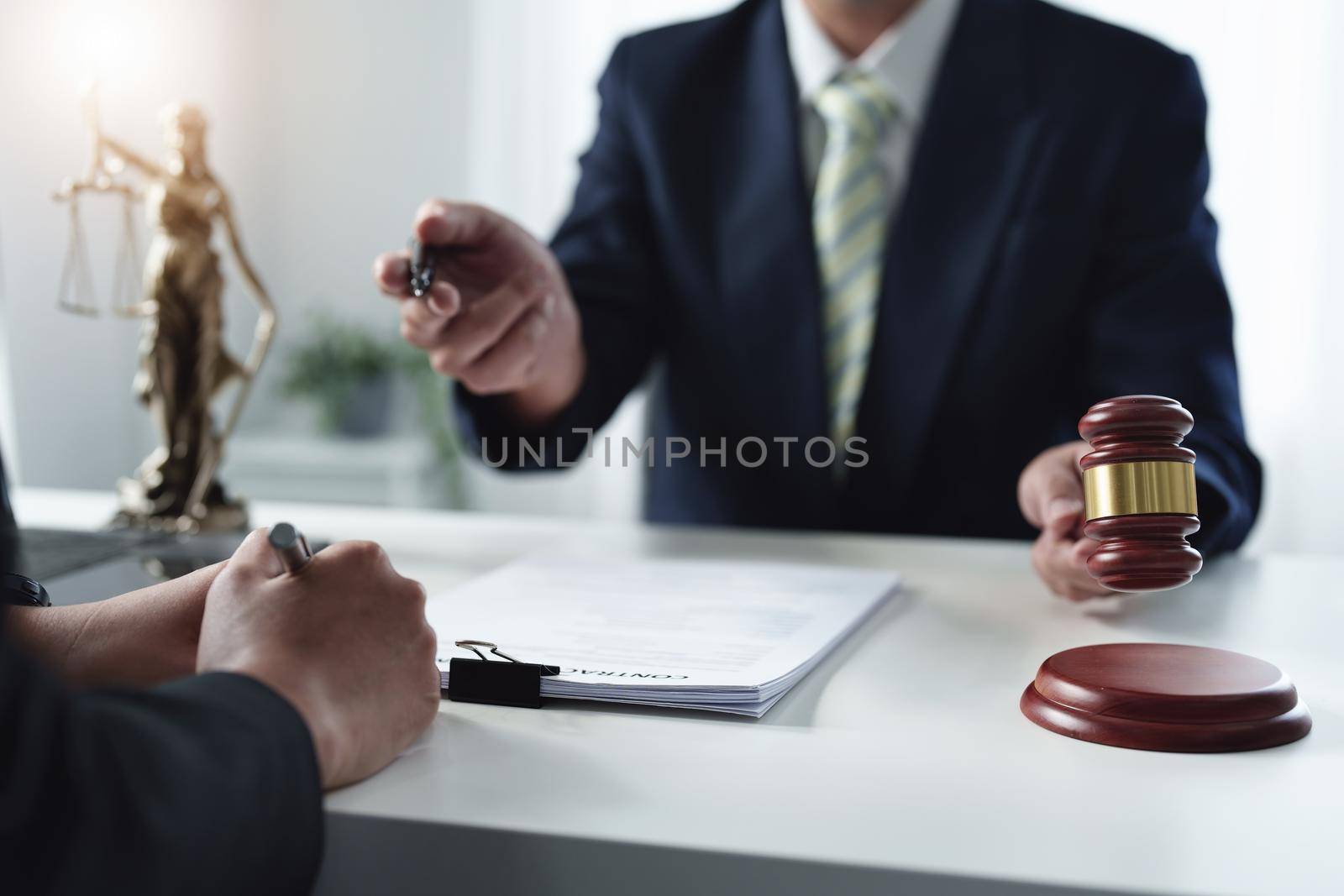 Focus at gavel, Attorney or Lawyer holding a pen is consulting with a client to explain the pattern of answering questions before going to court to decide a lawsuit. by Manastrong