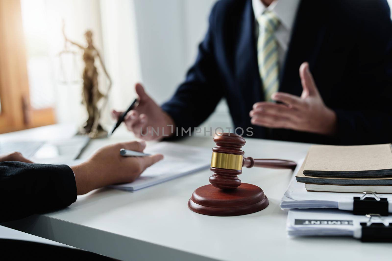 Focus at gavel, Attorney or Lawyer holding a pen is consulting with a client to explain the pattern of answering questions before going to court to decide a lawsuit. by Manastrong