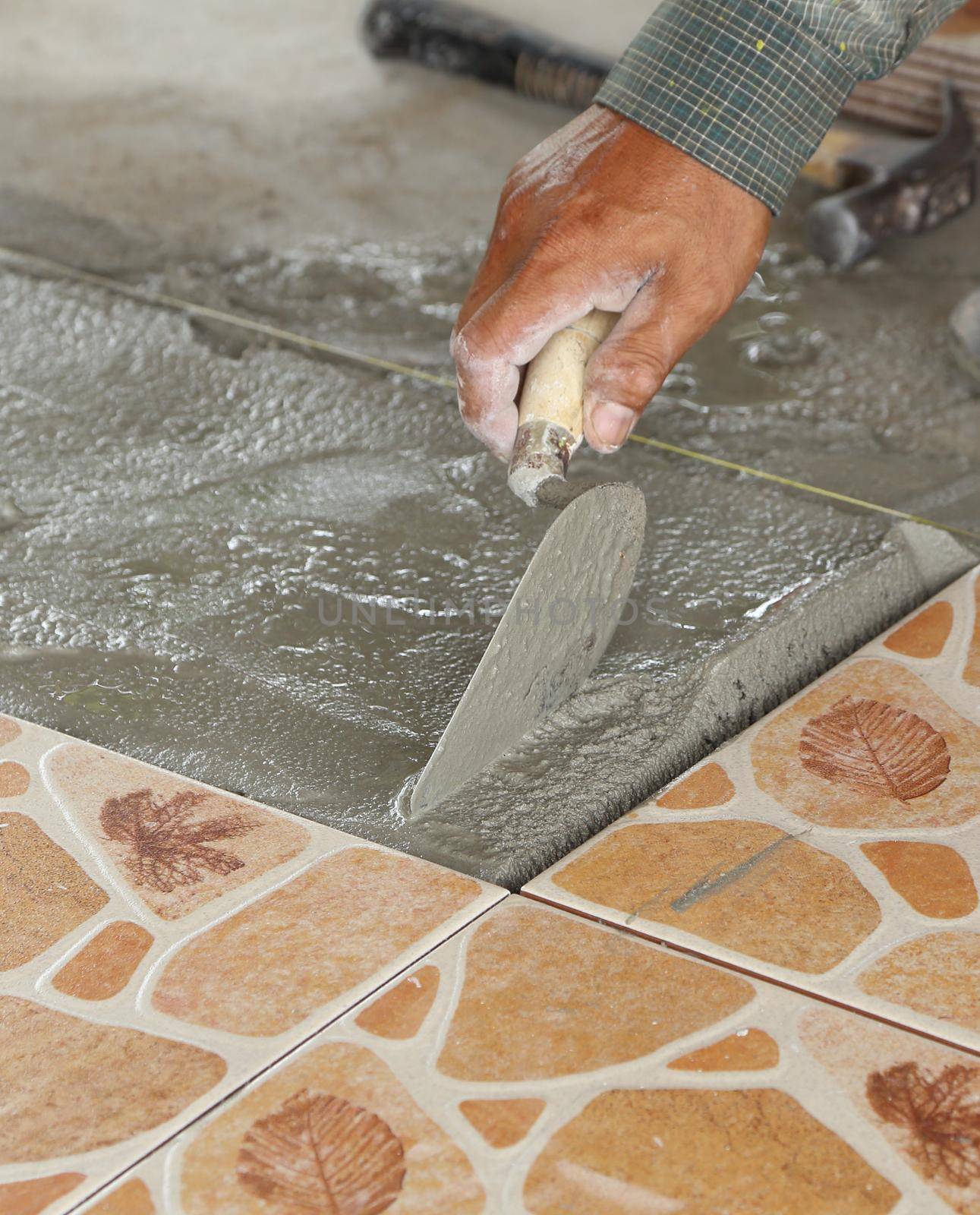 renovation - handyman laying tile, trowel with mortar