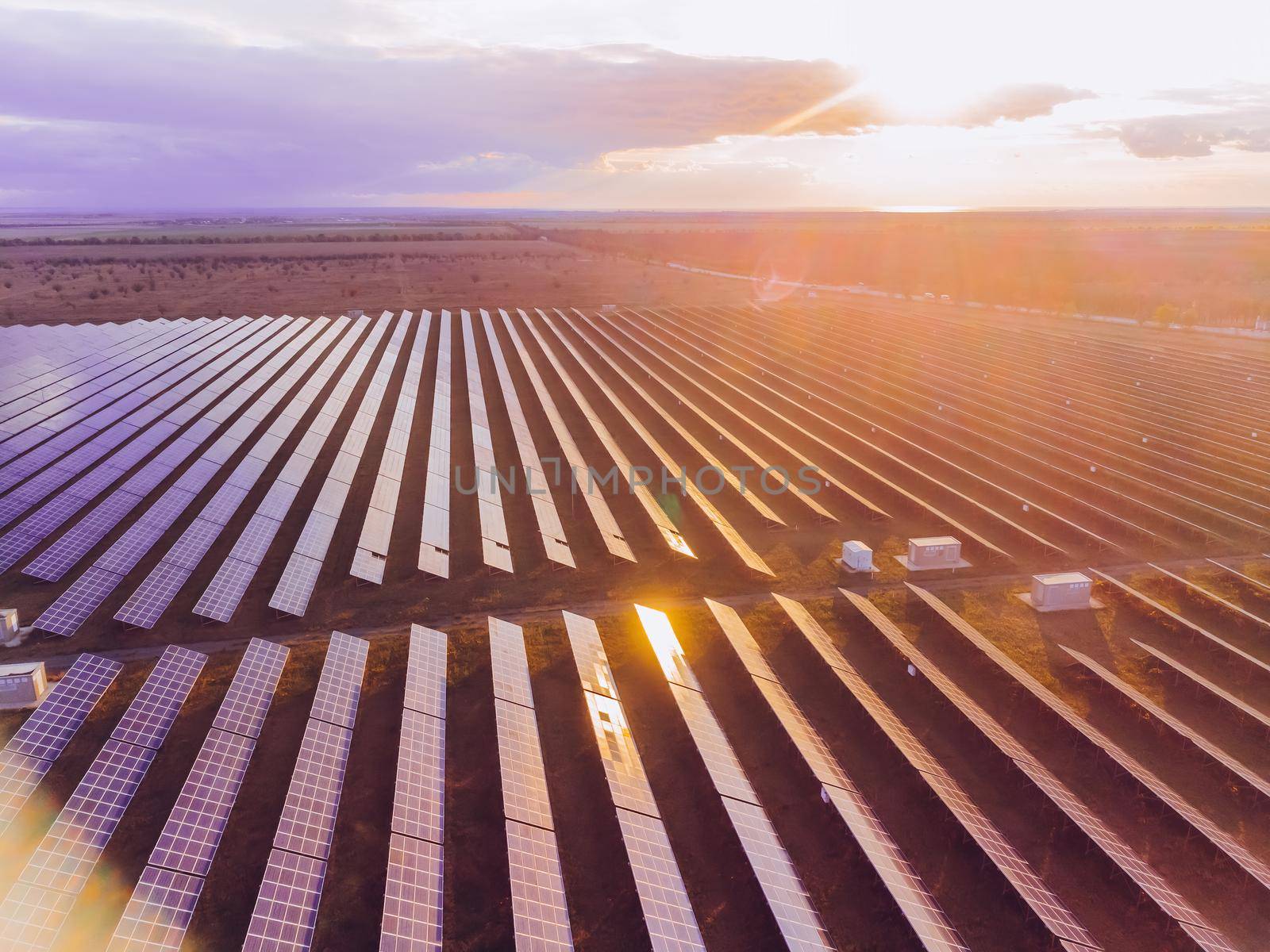 Aerial top view of a solar panels power plant. Photovoltaic solar panels at sunrise and sunset in countryside from above. Modern technology, climate care, earth saving, renewable energy concept