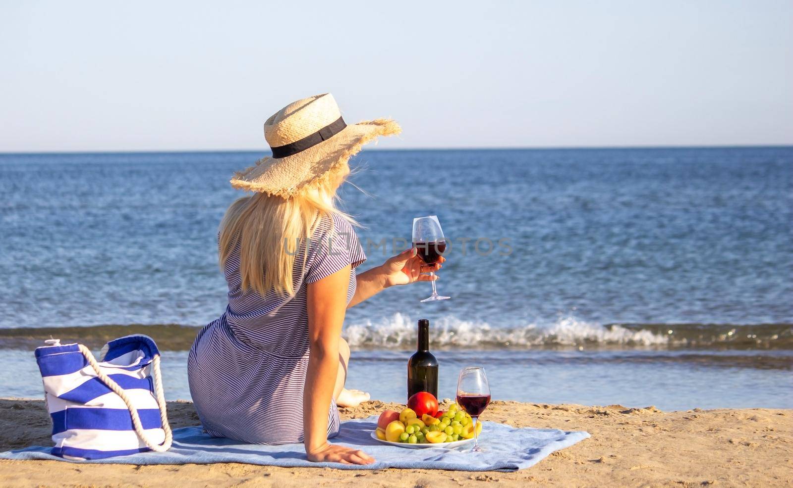 Beautiful smiling woman with a glass of wine on the beach. Fruit red wine. by Anuta23