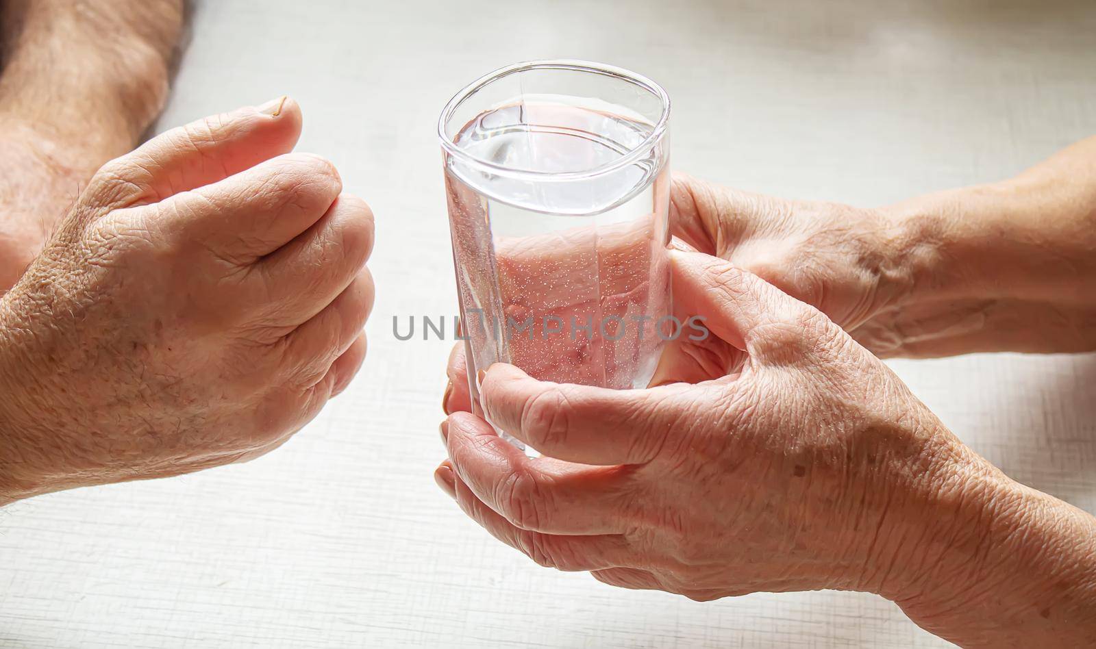 Grandma gives grandfather a glass of water. Selective focus. food.