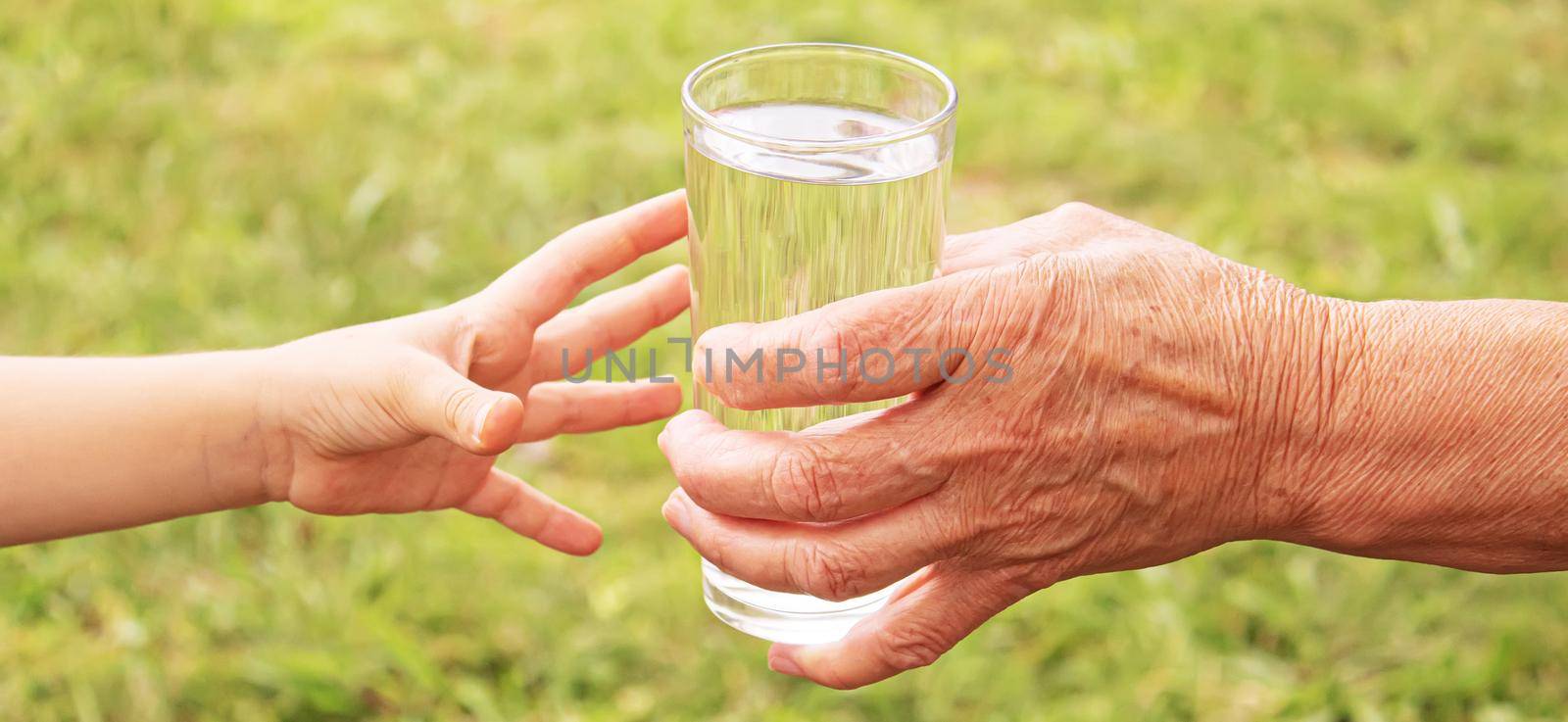 Grandmother giving a glass of clean water to a child. Selective focus. nature.
