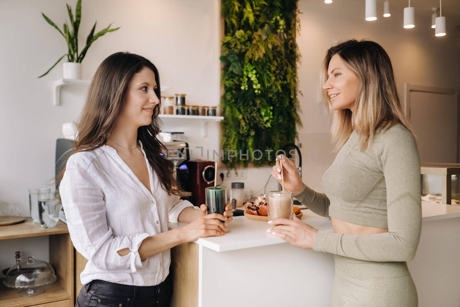 Two sporty-looking girls with cocktails in their hands discuss healthy eating and diet.