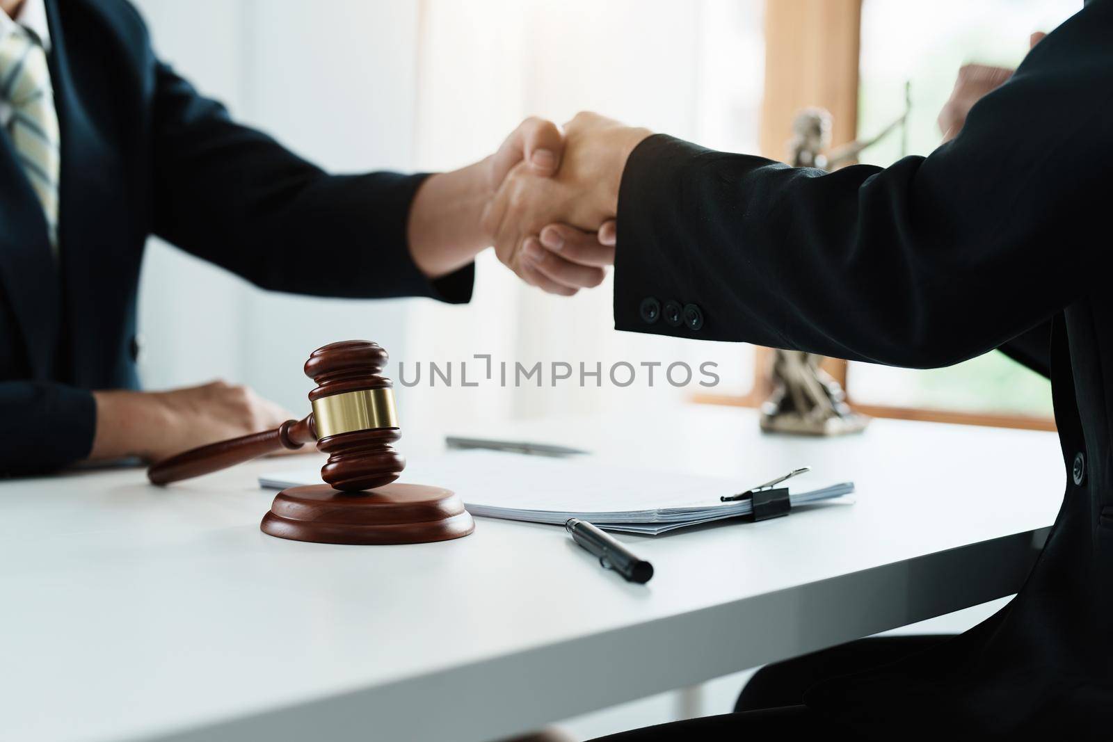 Law, consultation, agreement, contract, lawyer or attorney shakes hands to agree on the client's offer to be hired to fight the parties in court. by Manastrong