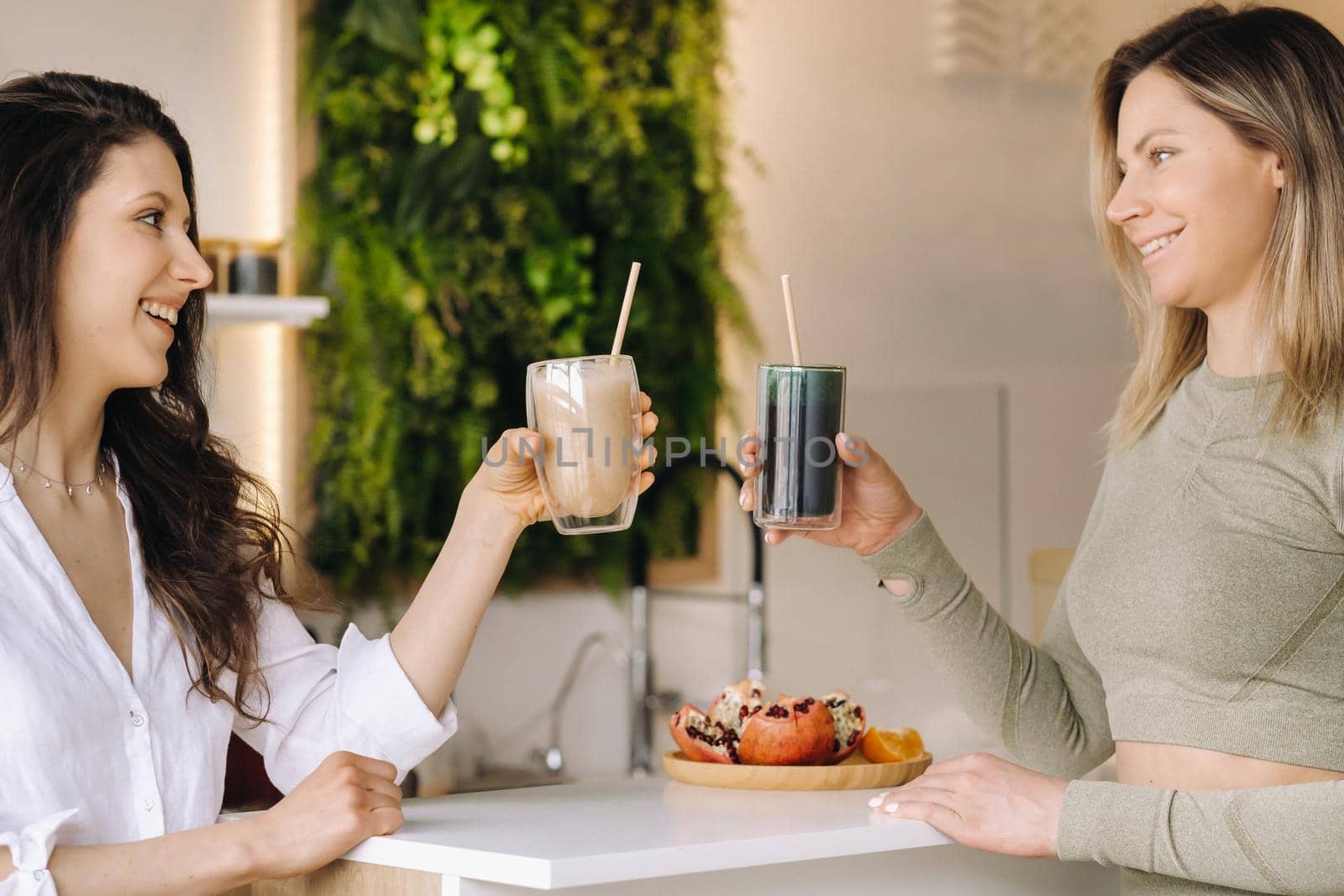 Two sporty-looking girls with cocktails in their hands discuss healthy eating and diet.