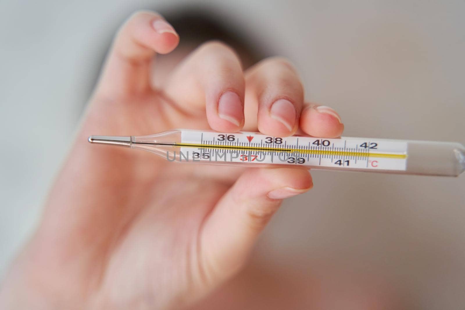 Girl holds a thermometer. High body temperature on a thermometer. Close-up.