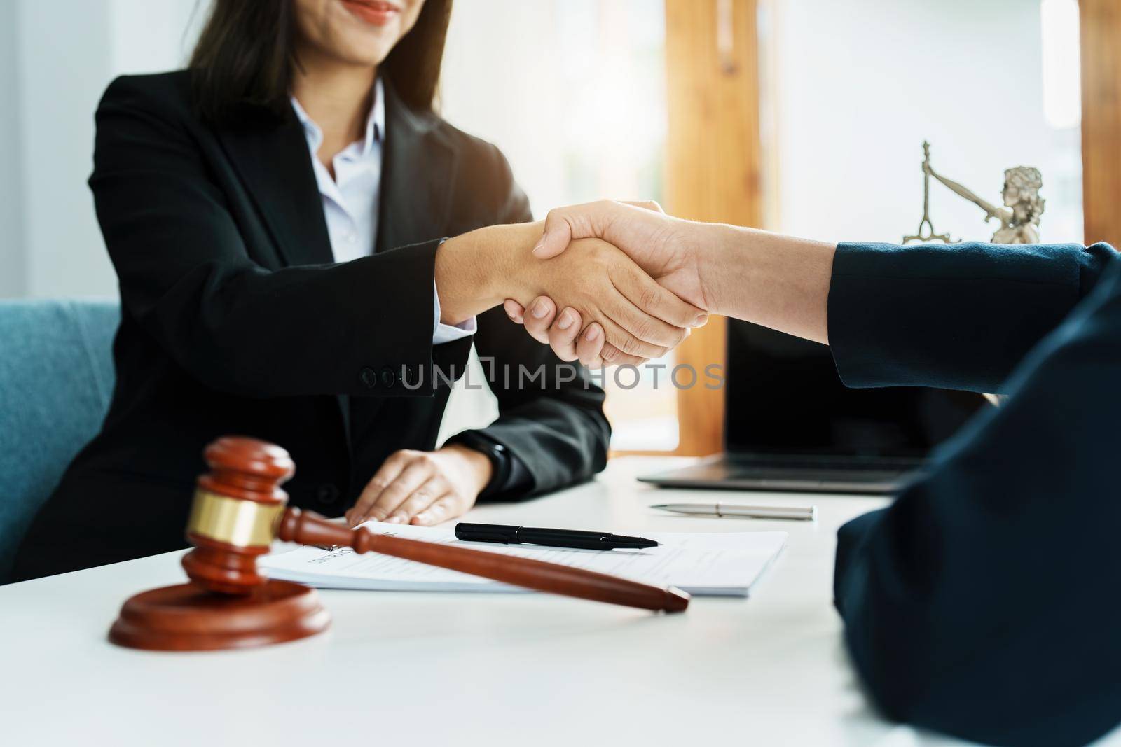 Law, consultation, agreement, contract, lawyer or attorney shakes hands to agree on the client's offer to be hired to fight the parties in court. by Manastrong