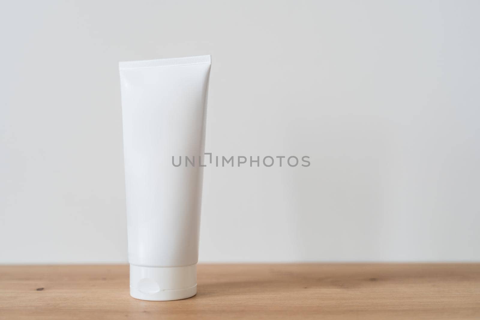 White tube cream mockup on a wooden table. Beauty and spa concept. Plastic blank tube for cream on white background