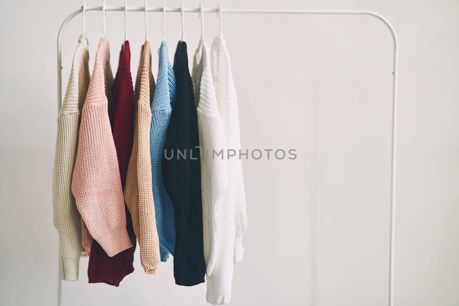 multicolored women's woolen sweaters on hangers. Sale in a fashion store. High quality photo