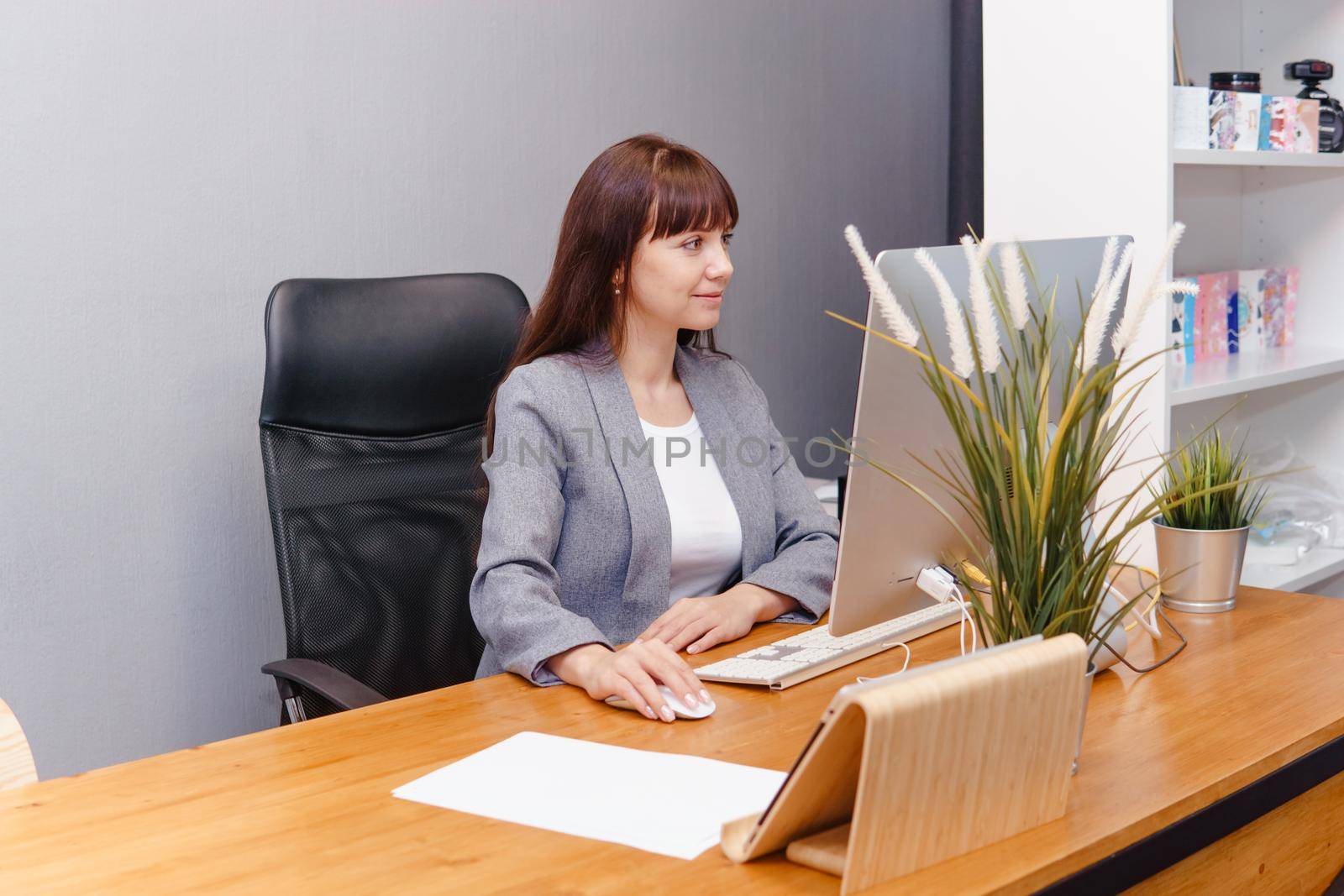 A brunette woman at a computer in the workplace. Business concept.