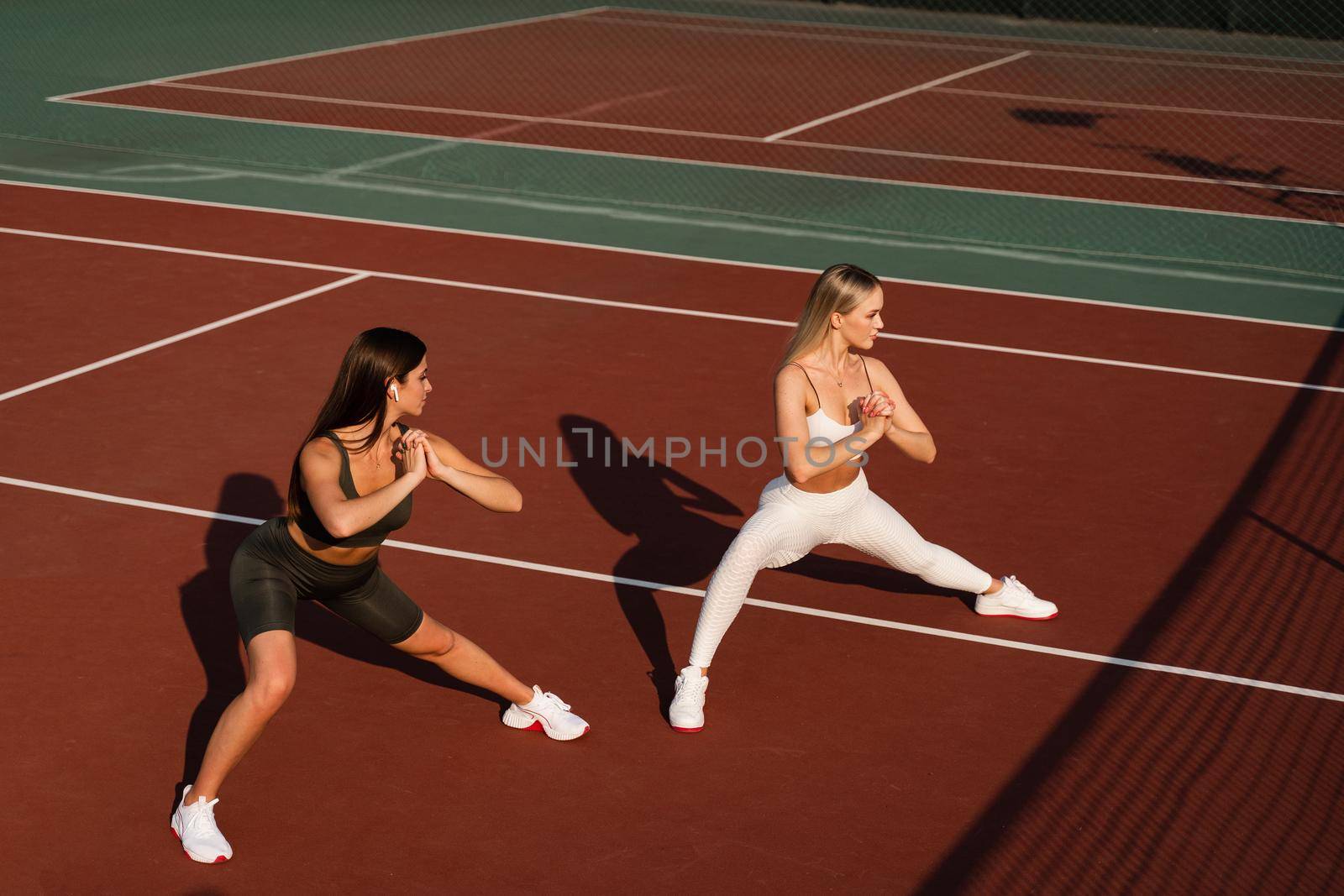 Group stretching of 2 fit girls. Active sport lifestyle. Outdoor training by Rabizo