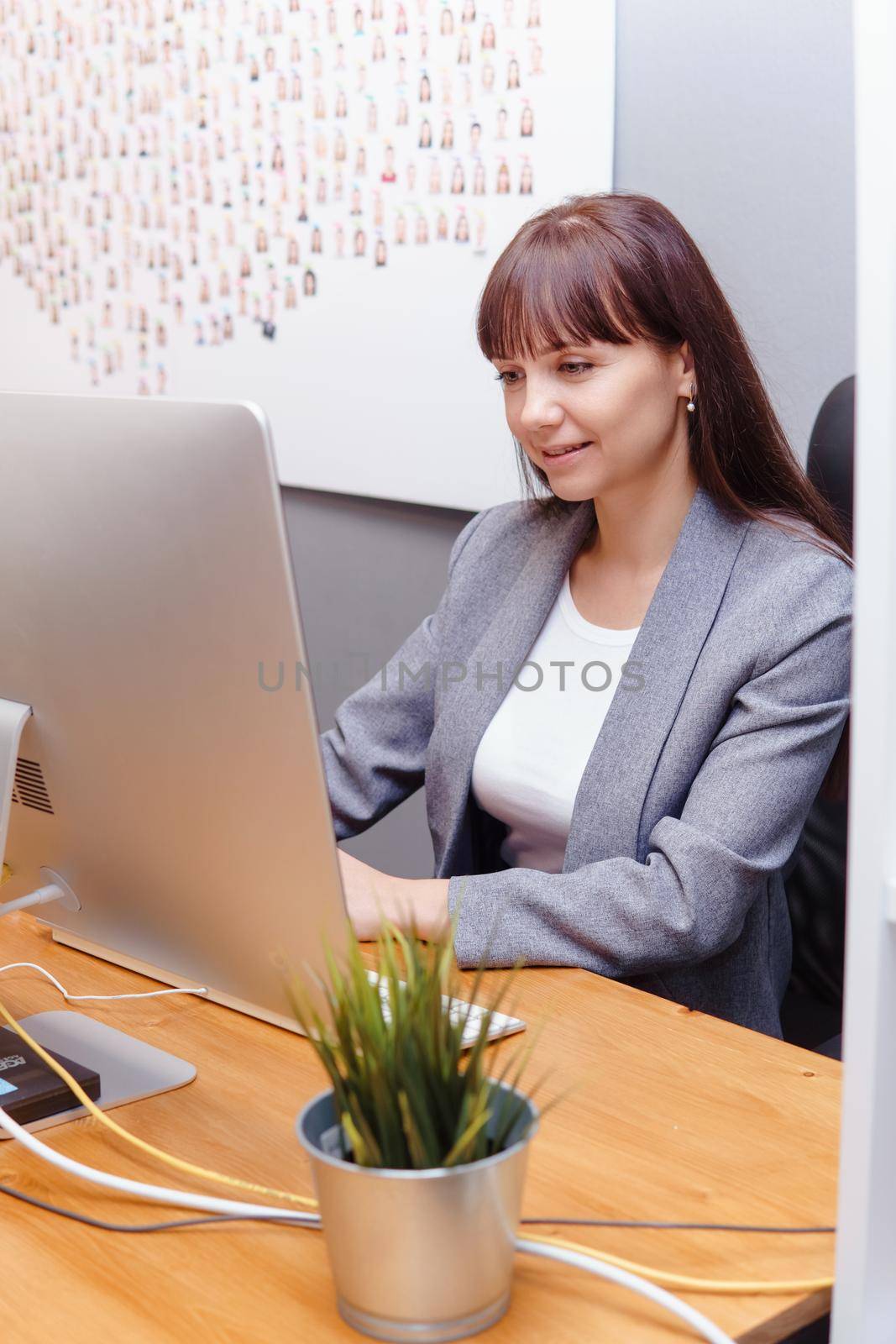 A brunette woman at a computer in the workplace. Business concept.