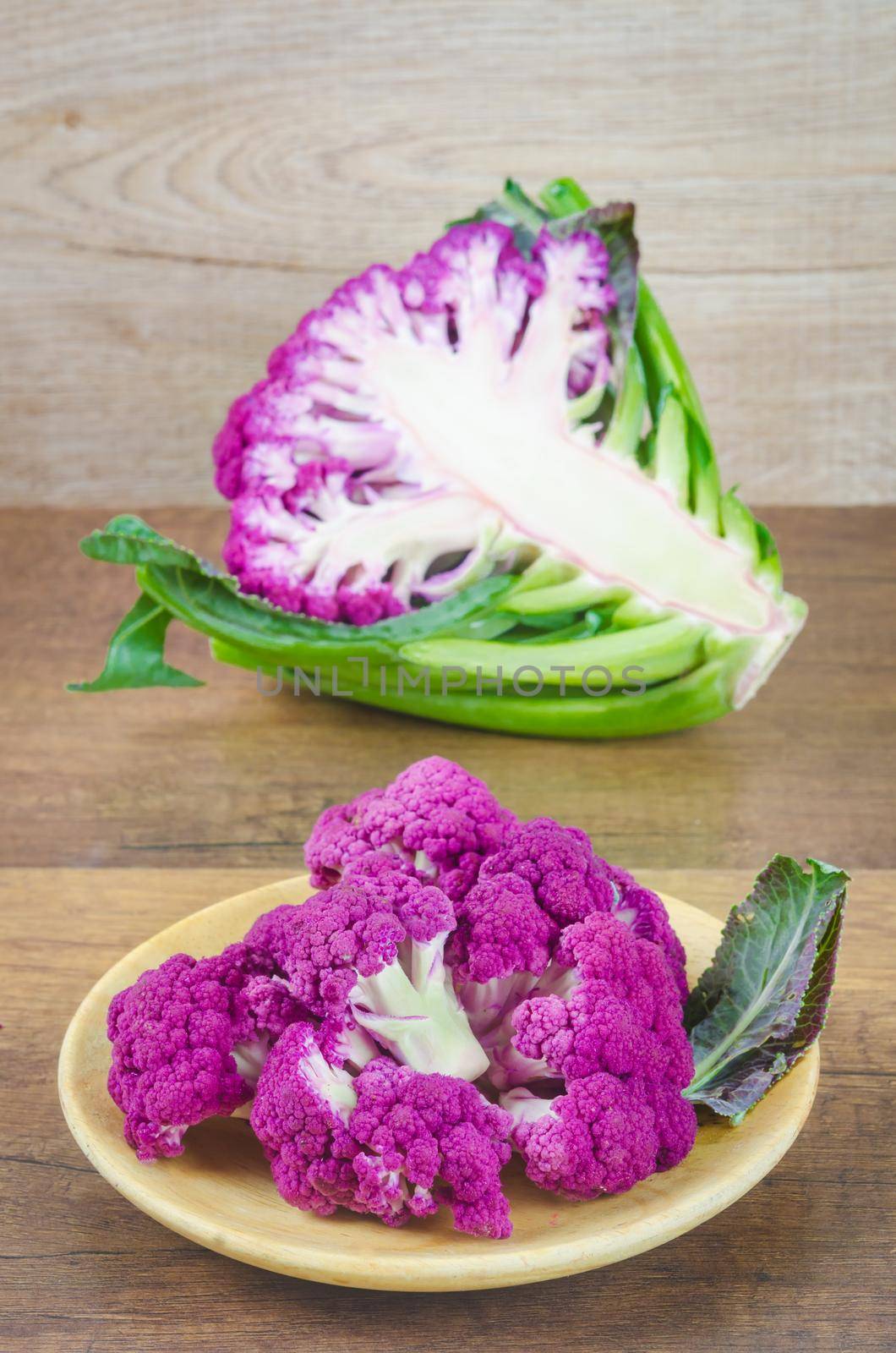 Freshness Purple Cauliflower on wooden background. by Gamjai