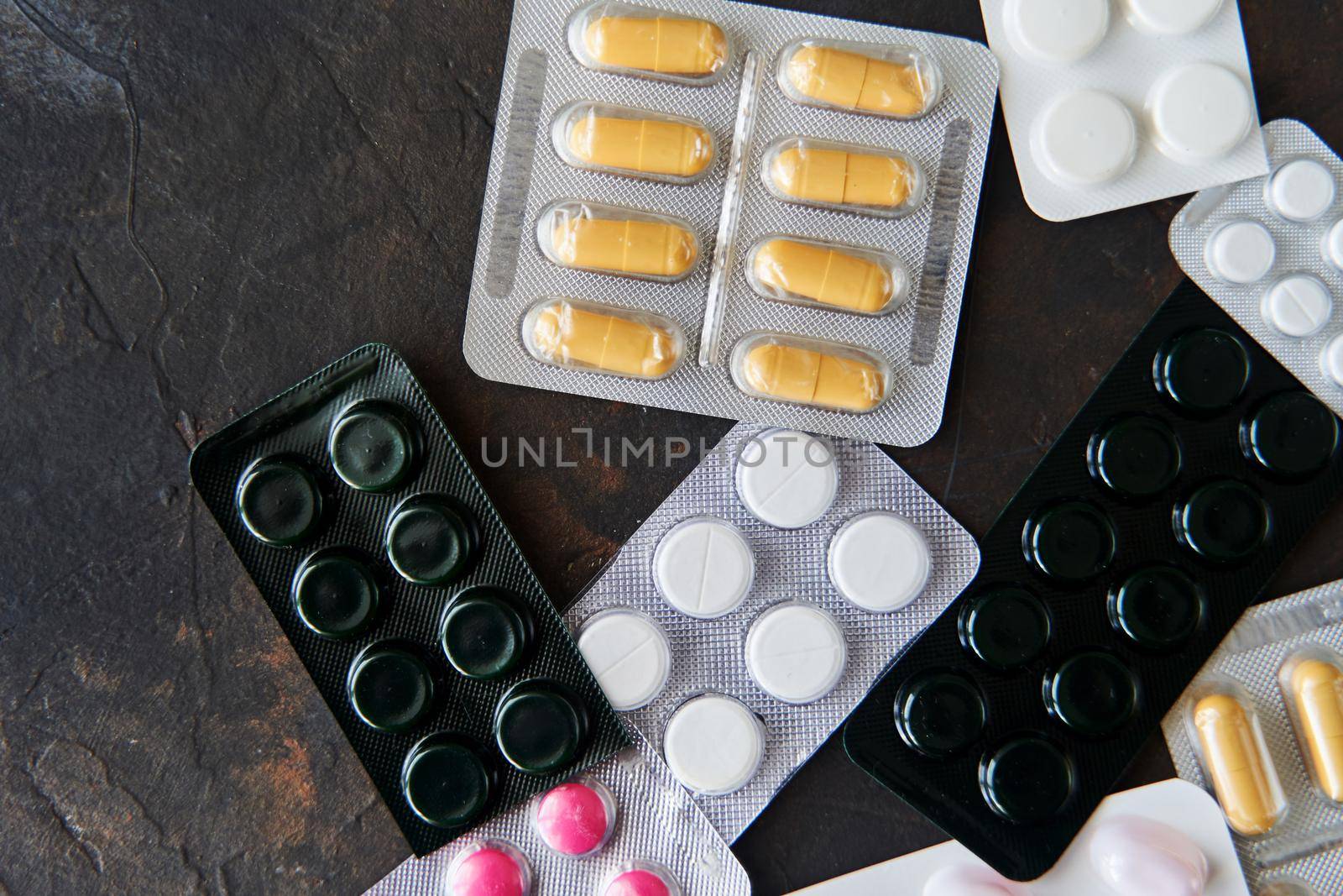 Pills capsules medicine health on dark background top view, medical pharmacy concept. Different pills on dark background with copy space.