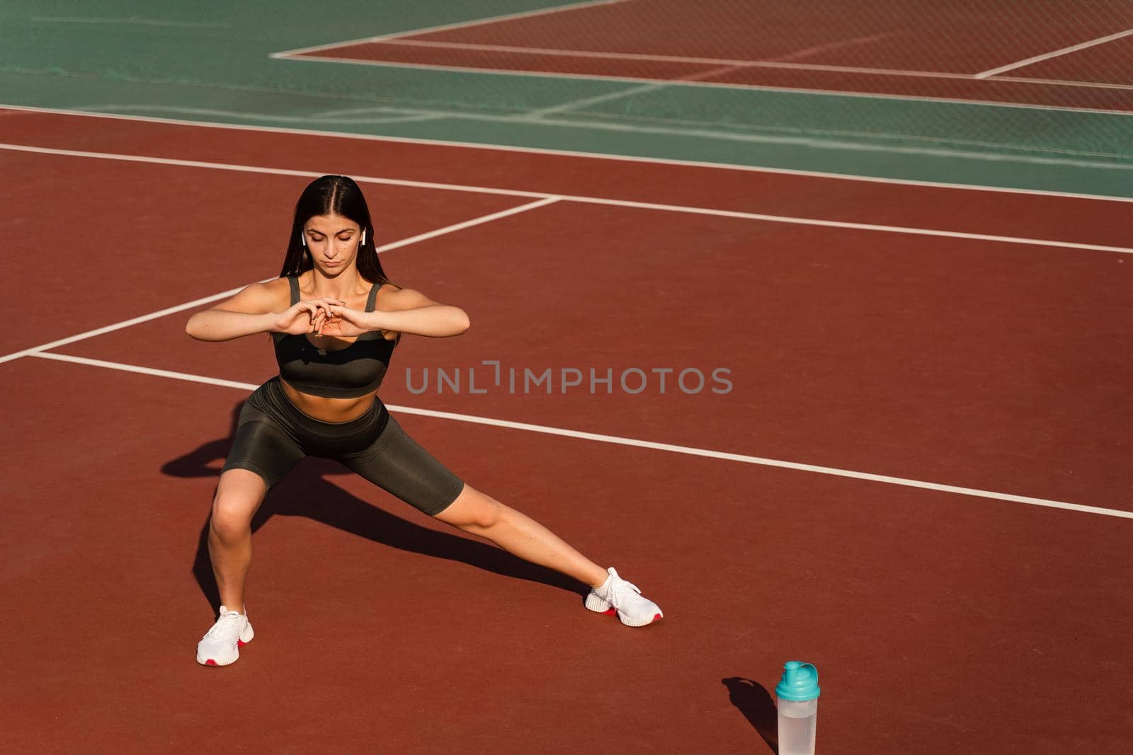 Fit girl does warm-up and stretching exercises before a street workout. Sports lifestyle. by Rabizo