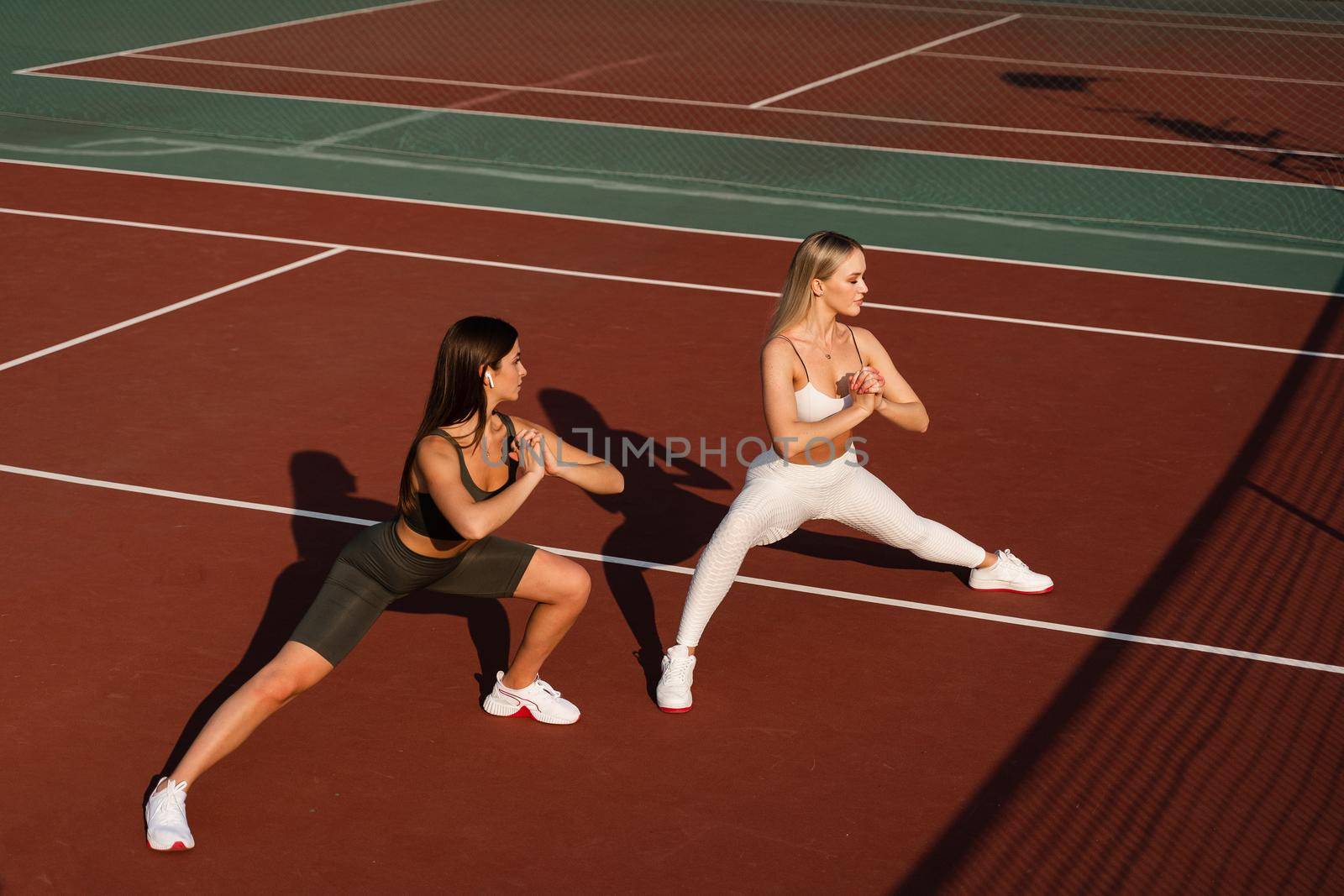 Group stretching of 2 fit girls. Active sport lifestyle. Outdoor training by Rabizo