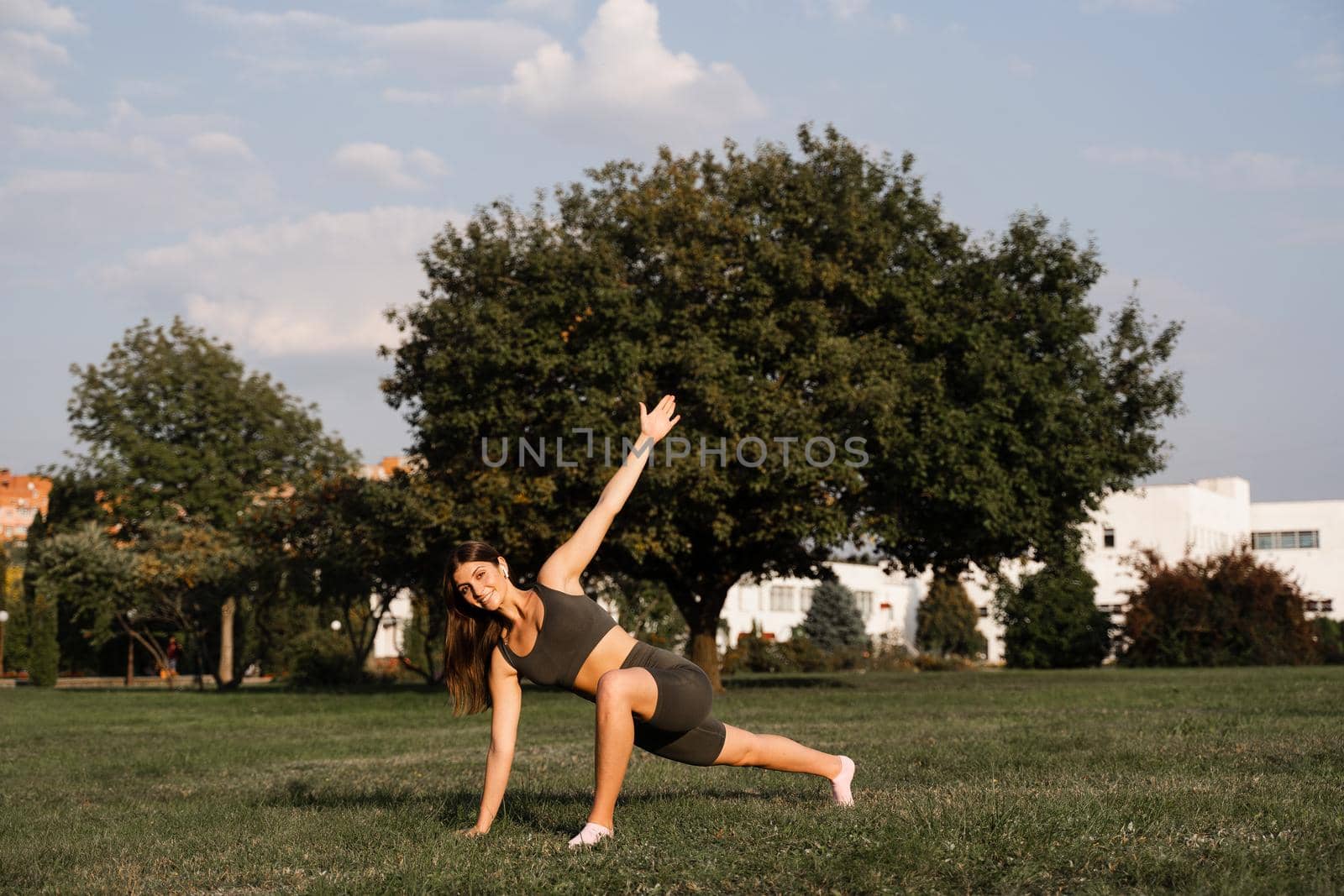 Fit girl training on green grass in the park. Outdoor workout. Sport lifestyle of active young woman