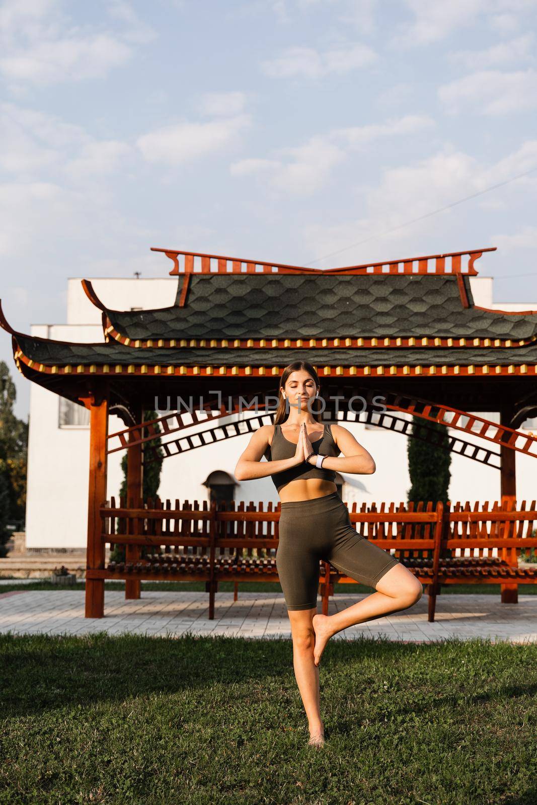 Asian fit girl meditates against the background of a Chinese gazebo. Relaxation and meditation outdoors