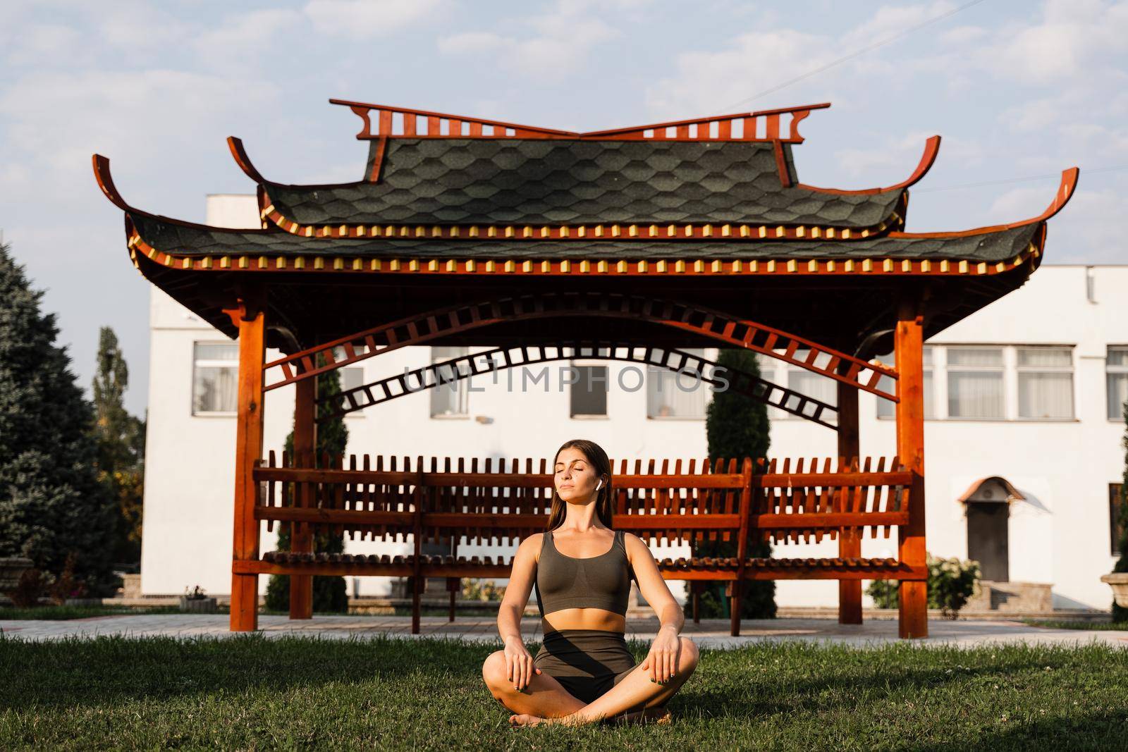 Asian fit girl is sitting in lotus position and meditating. Meditation and relaxation outdoors