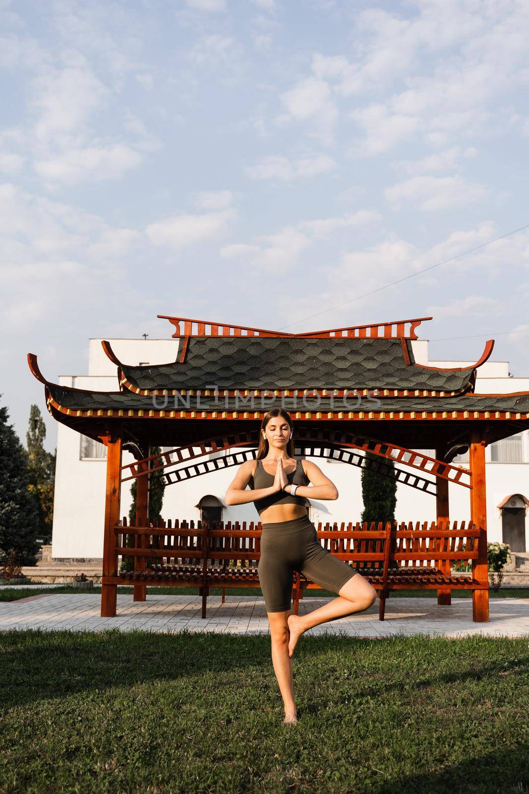 Asian fit girl meditates against the background of a Chinese gazebo. Relaxation and meditation outdoors