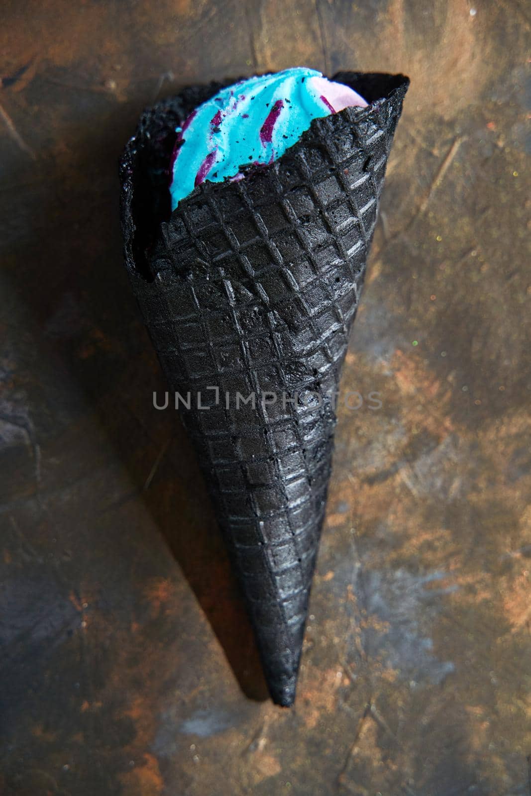 Black waffle cones of ice cream on a dark background, top view. Trendy ice cream