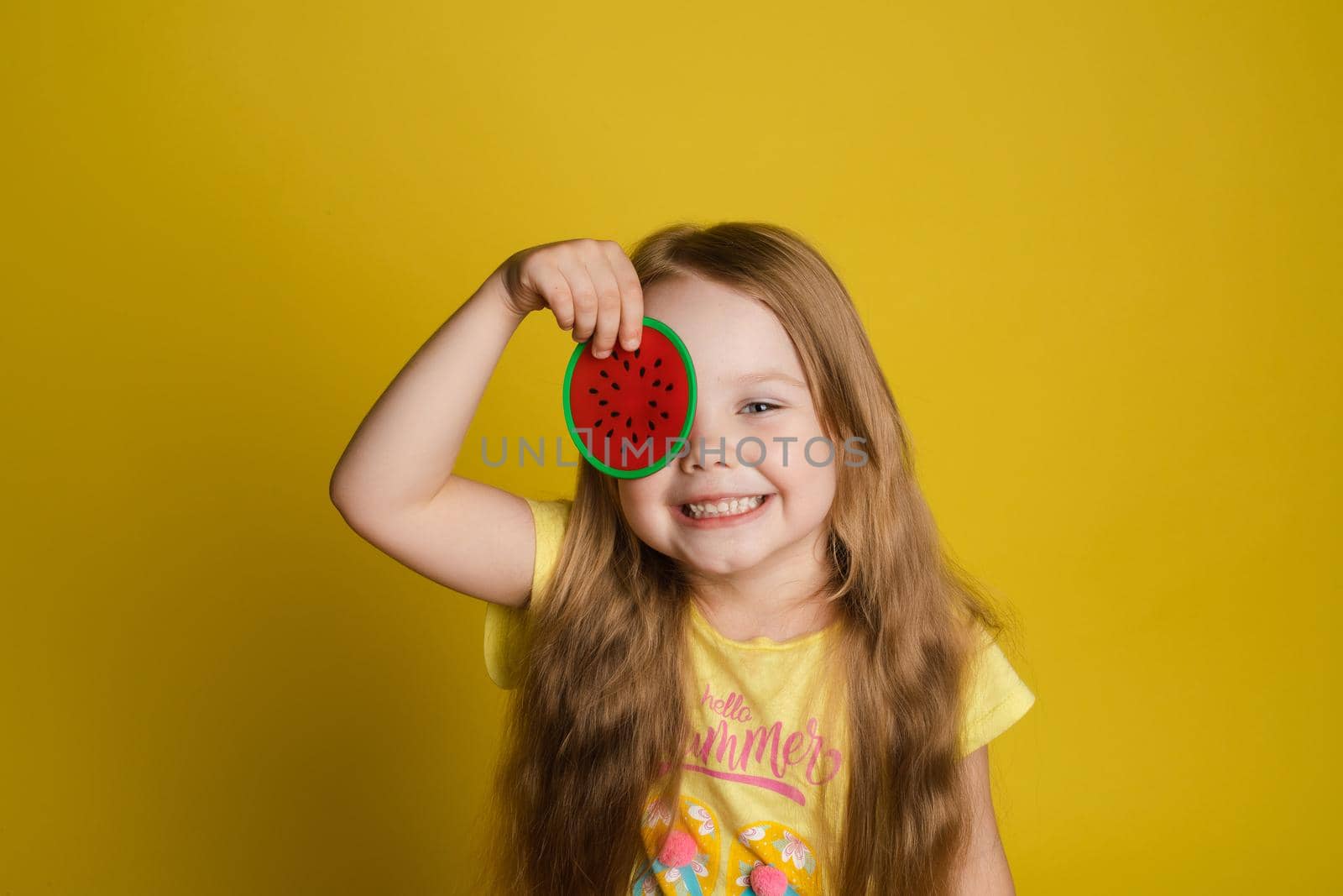 Portrait of smiling little girl holding slice of lemon near eye looking at camera medium close-up by StudioLucky