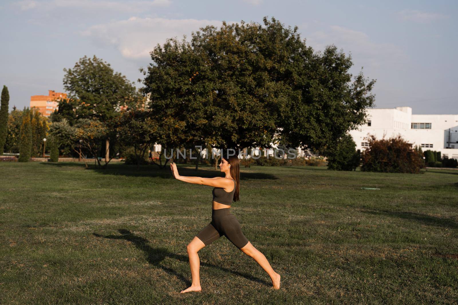 Qigong meditation exercises outdoor. Fit asian girl does chinese training on the green grass in the park