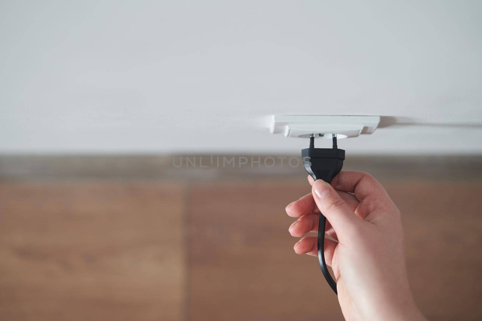 A young girl inserts a plug into an outlet. Young woman plugs the phone charger into the socket. High quality photo