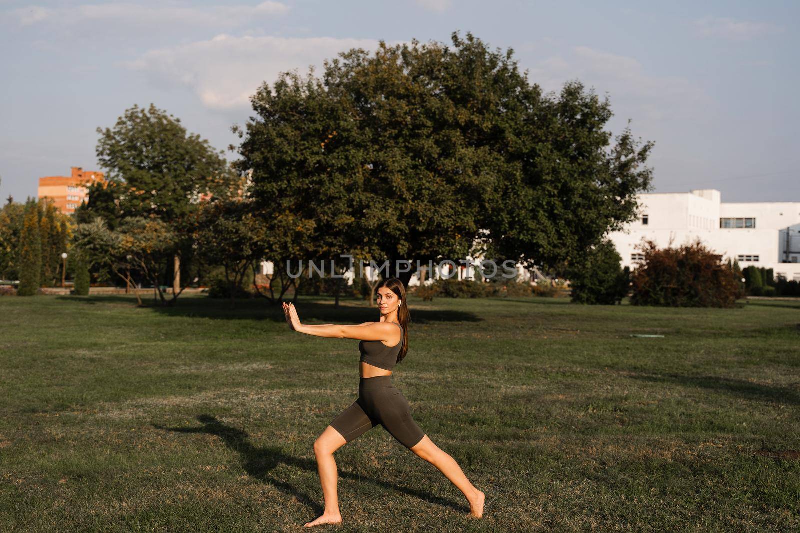 Qigong meditation exercises outdoor. Fit asian girl does chinese training on the green grass in the park