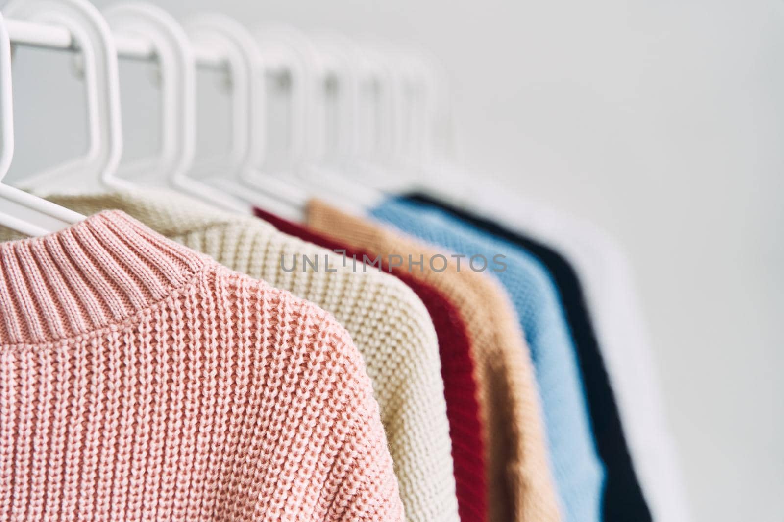multicolored women's woolen sweaters on hangers. Sale in a fashion store by driver-s