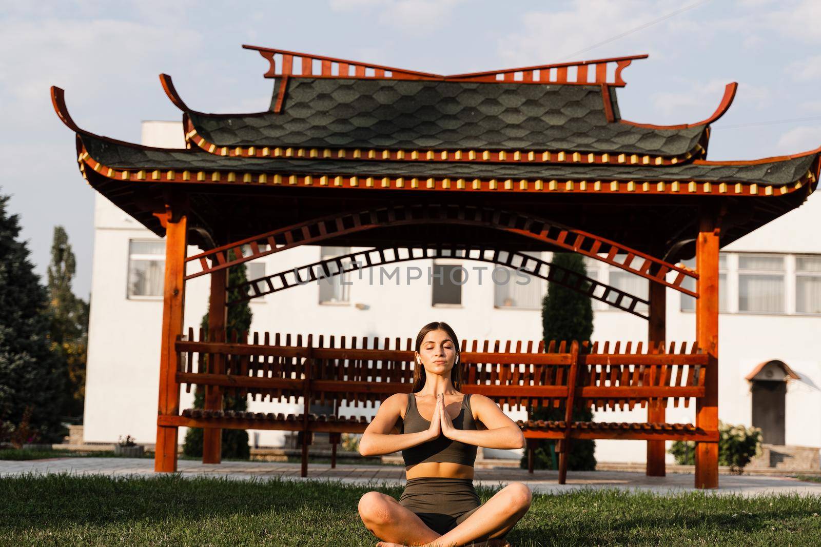 Asian fit girl is sitting in lotus position and meditating. Meditation and relaxation outdoors