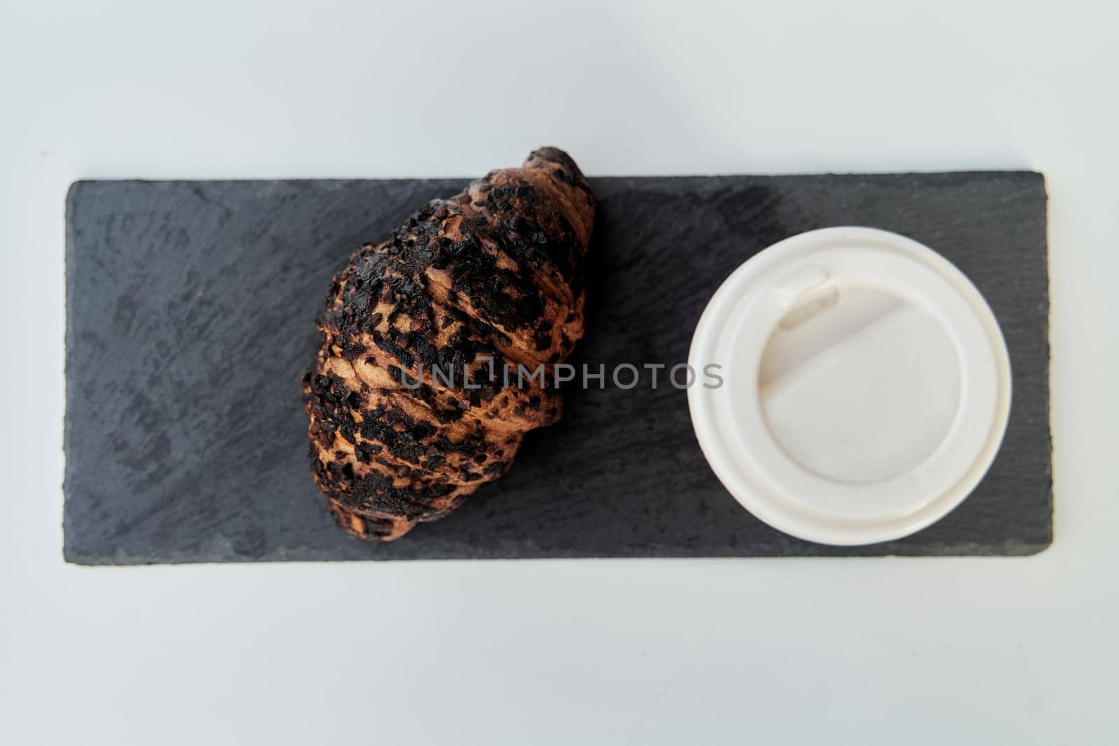 Red cup with coffee and a croissant on a table in a cafe. by driver-s