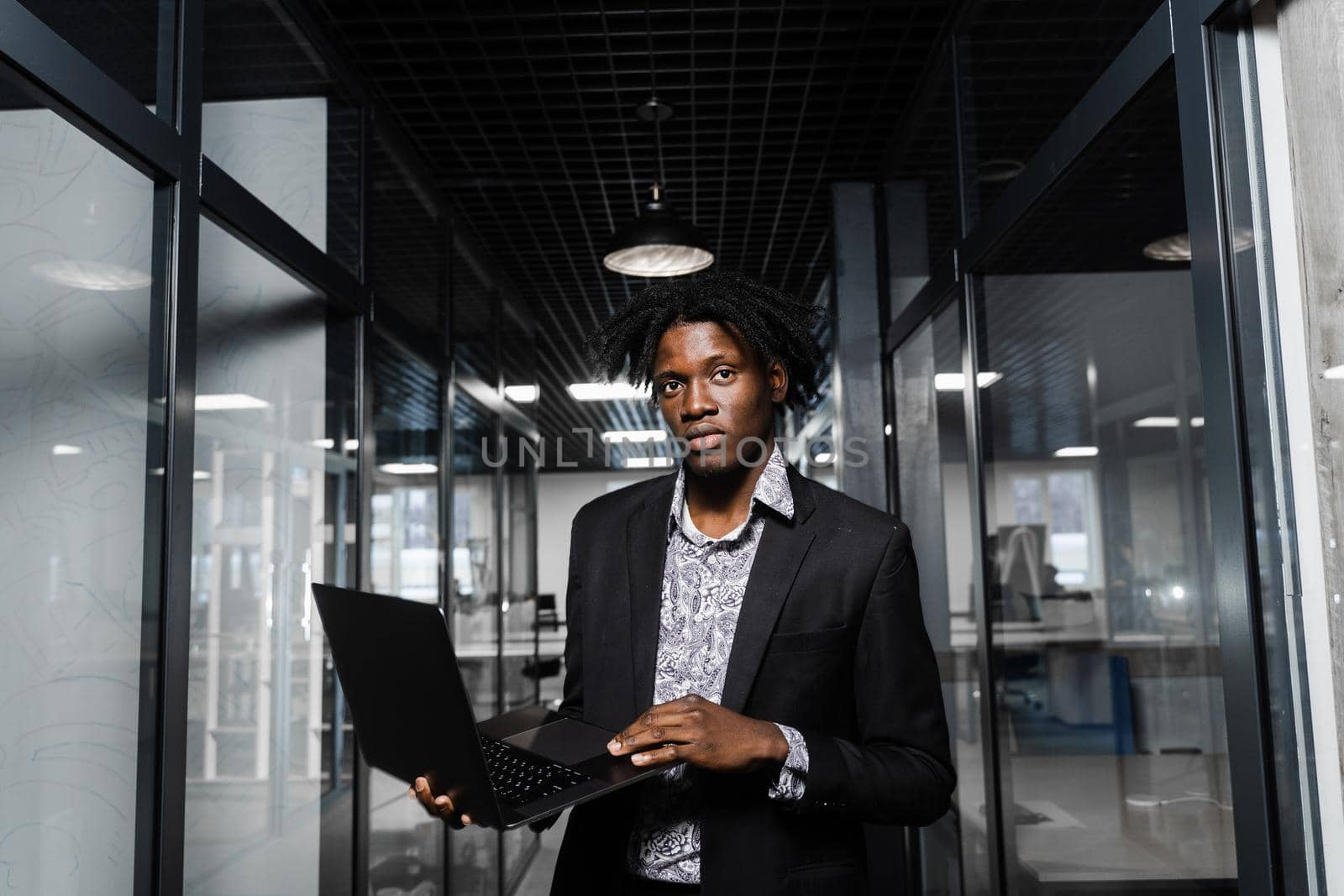 Confident black business man with laptop working online with his colleagues. Handsome african manager in the office