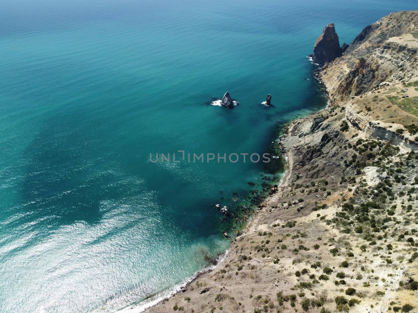 Aerial view on calm azure sea and volcanic rocky shores. Small waves on water surface in motion blur. Nature summer ocean sea beach background. Nobody. Holiday, vacation and travel concept by panophotograph