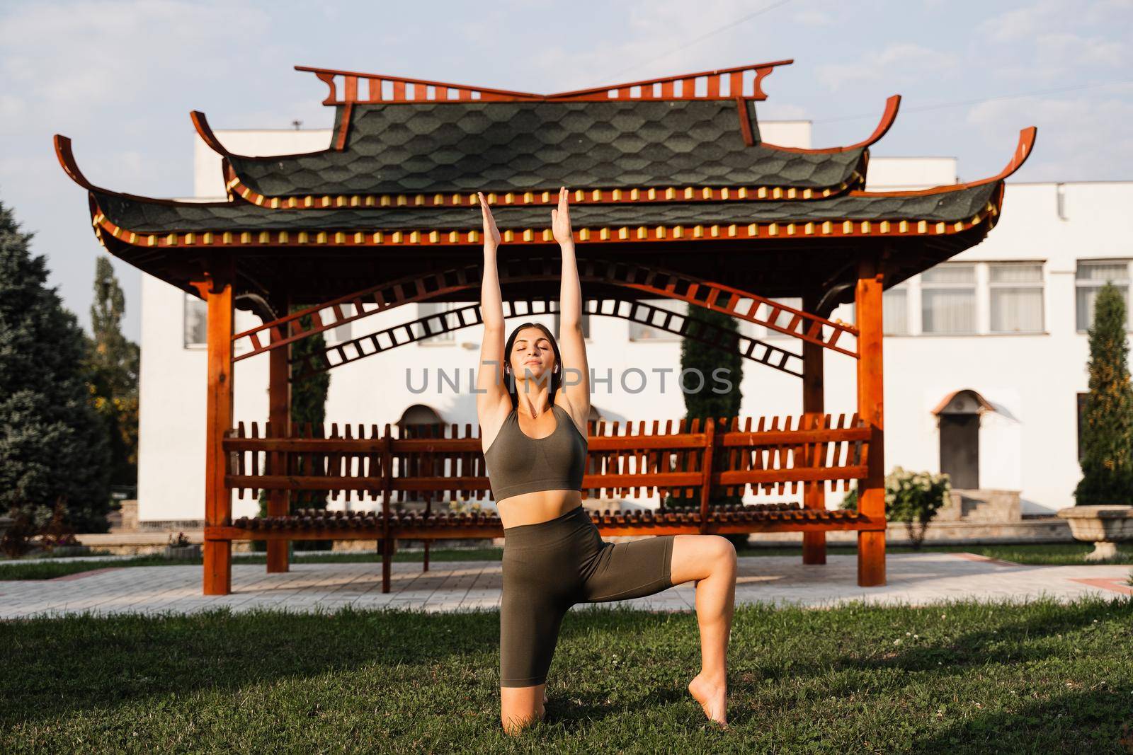 Meditation and relaxation outdoor. Asiat fir girl is meditating near chinese gazebo