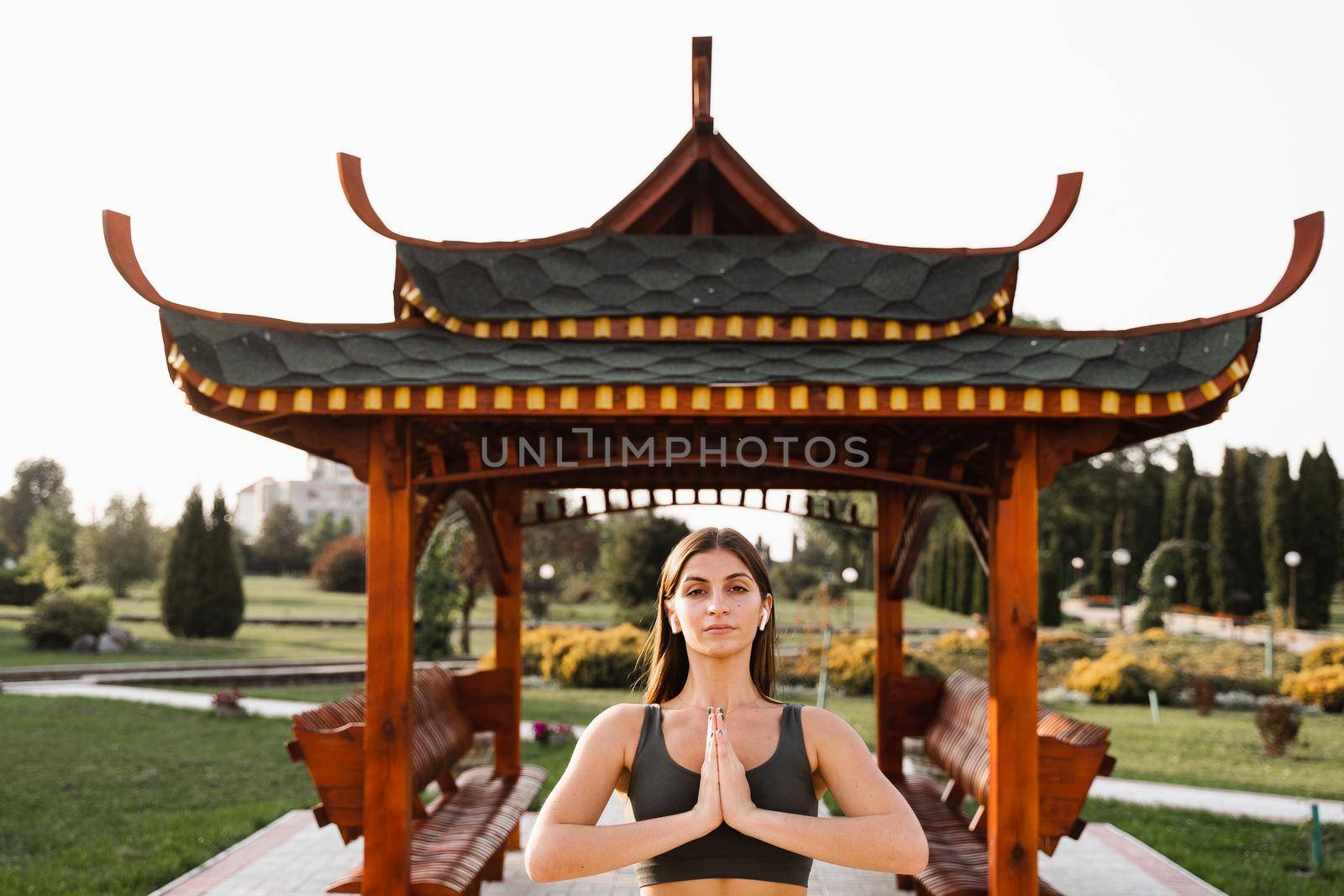 Fit girl pray and meditating near chinese gazebo. Praying and meditation outdoors