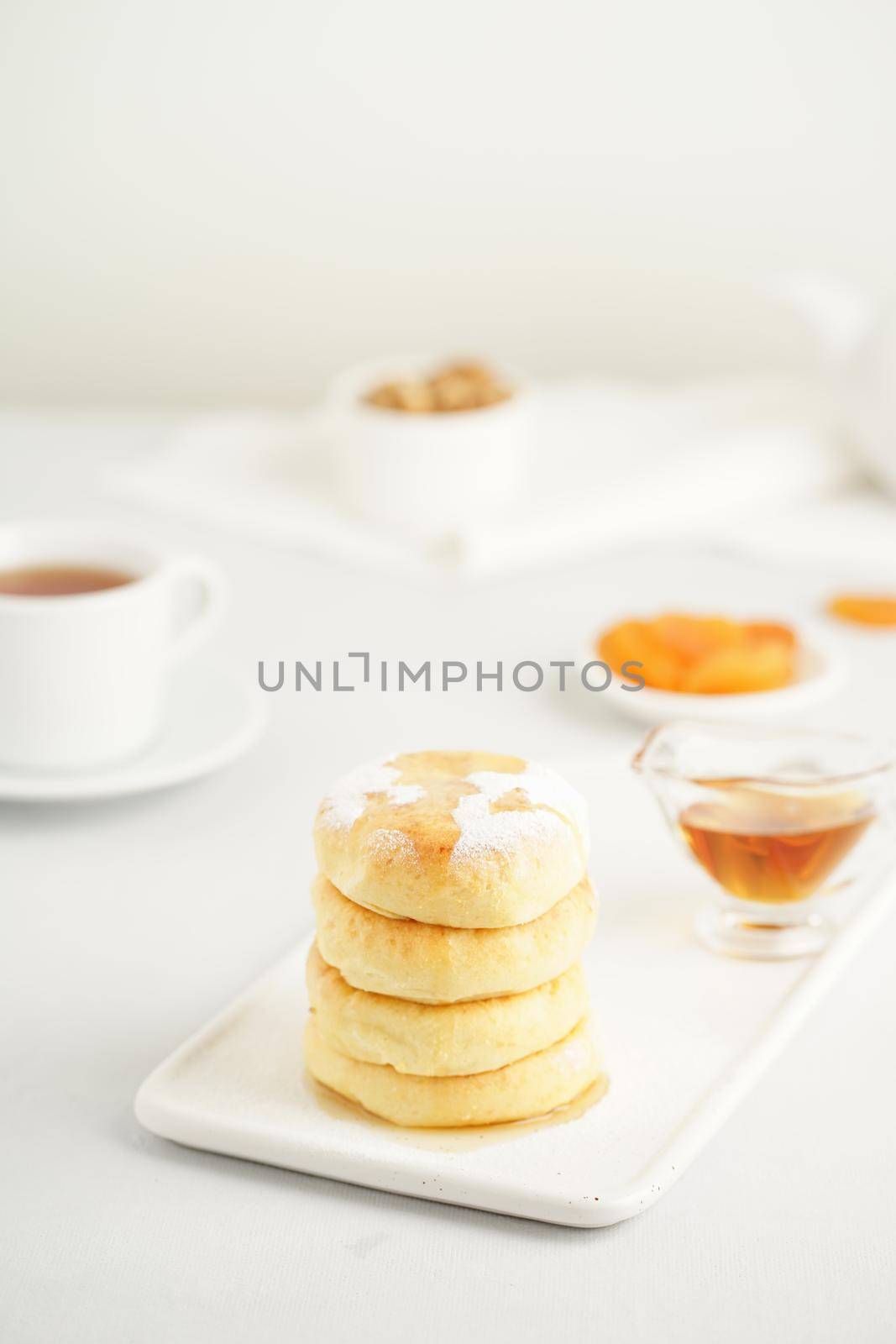 Fried cheese cakes, sweet cheese pancakes on white plate on white background by NataBene
