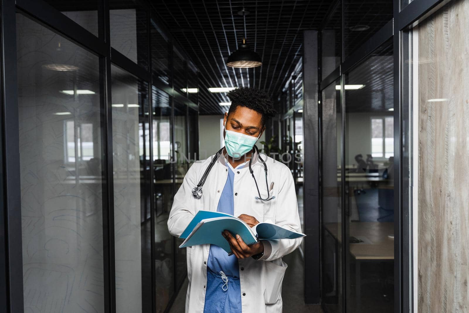 African doctor in mask with books in medical clinic. Black medical student study in university