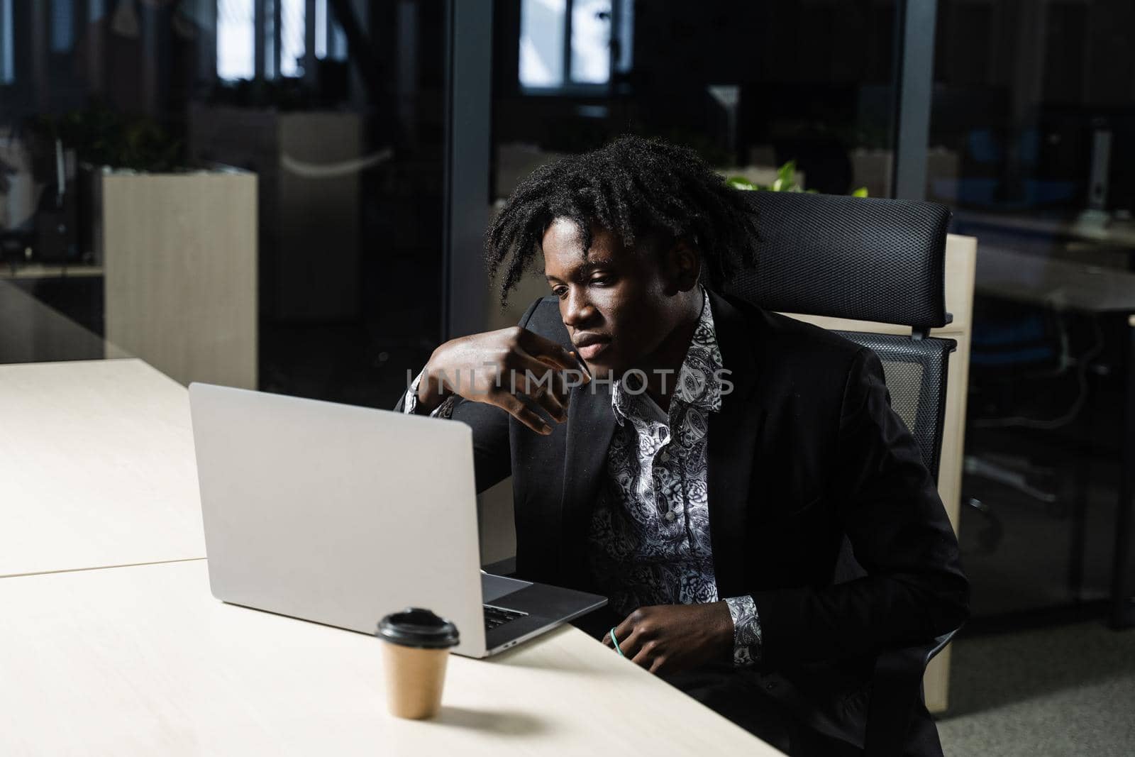 Black business man with laptop is working online in the office. Handsome african manager is doing remote work in coworking space