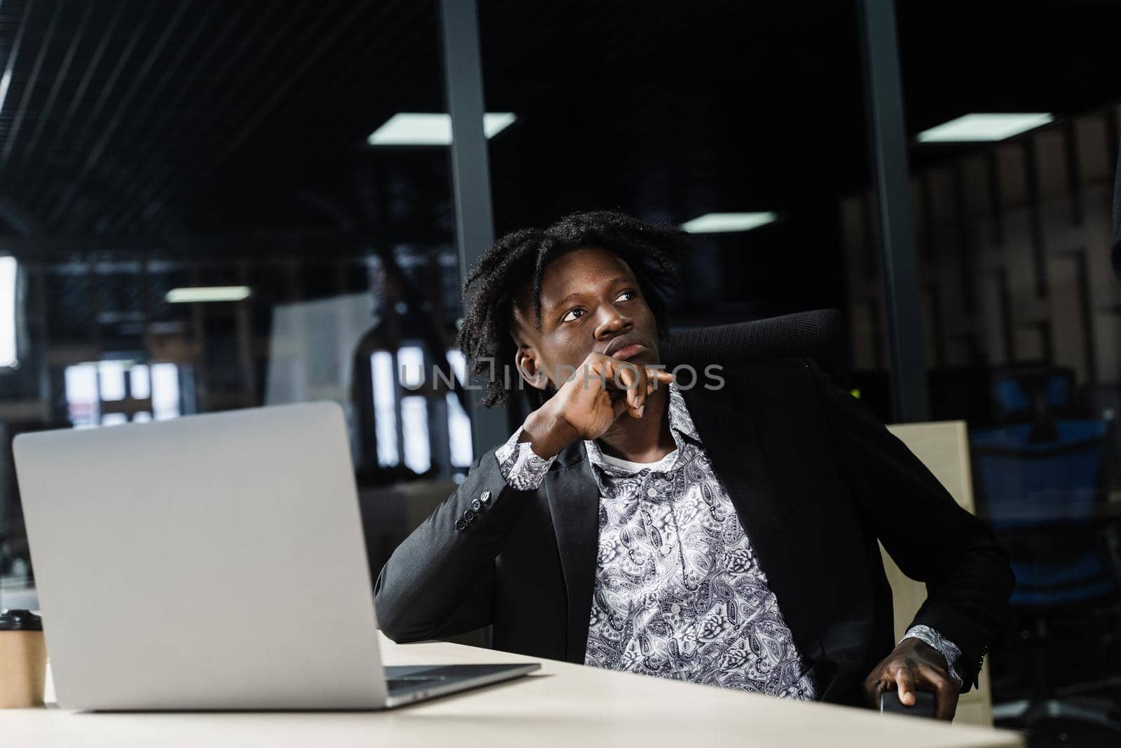 Black hipster man with laptop is listening a speech of his colleagues. Teamwork. Offline job