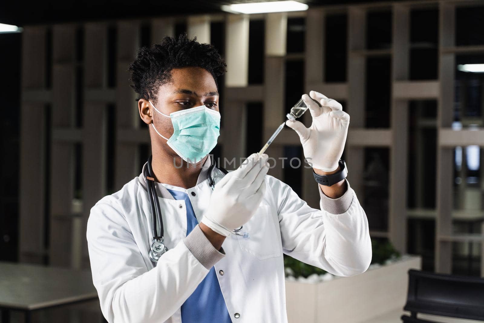 African doctor in a medical mask prepares to inject coronavirus covid-19 vaccine. Black doctor in white medical robe with syringe for making vaccination