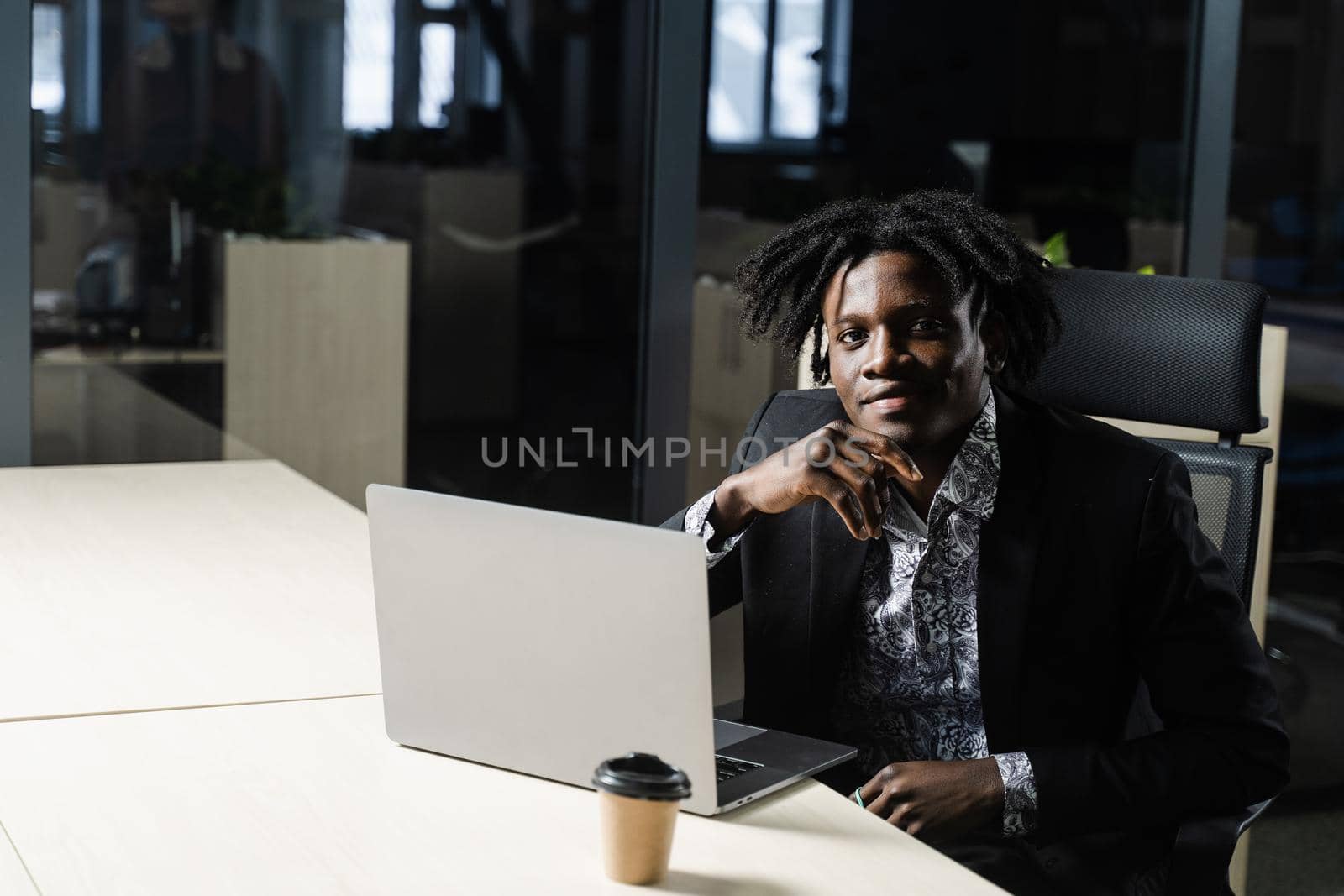 Black business man with laptop is working online in the office. Handsome african manager is doing remote work in coworking space. by Rabizo