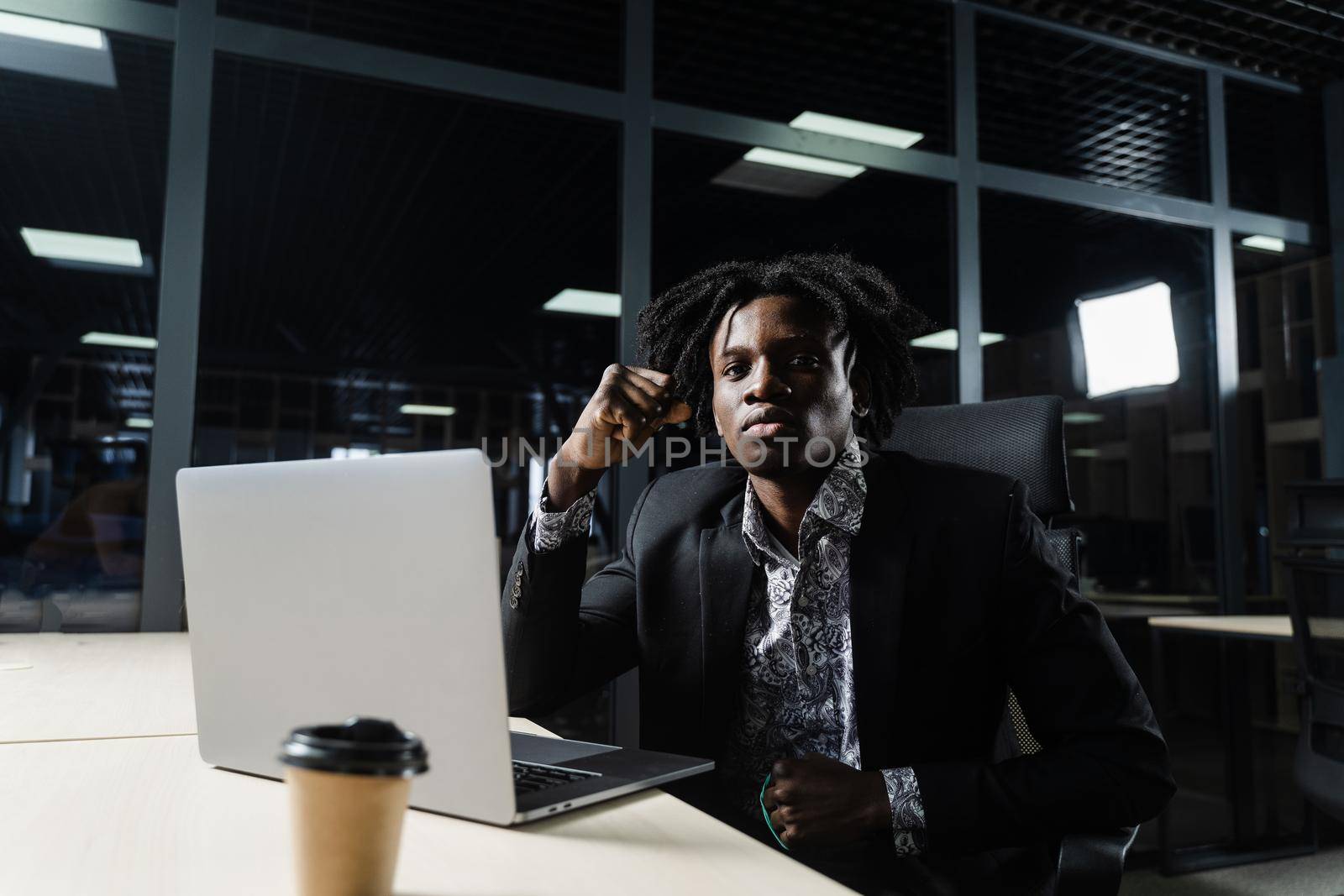 Happy black man clenched fists and rejoice finishing his online job on laptop. Working online in coworking space