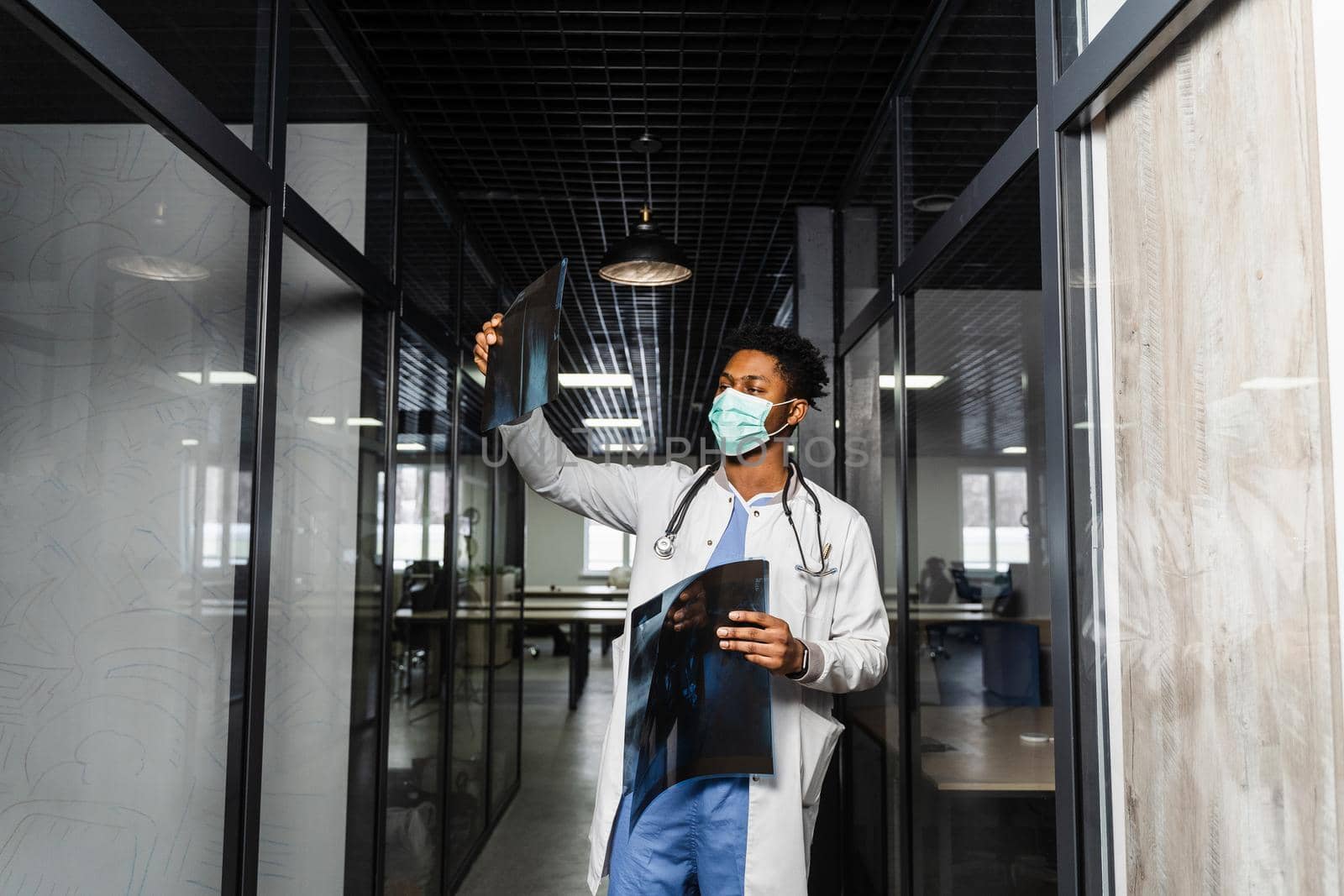 African doctor examines x-rays in a medical clinic. Black student in medical mask is studying and looking at ct scans