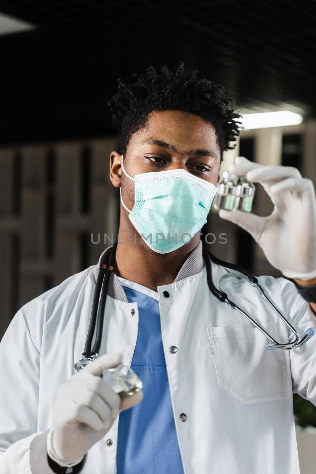 Black doctor with 3 doses of vaccine. Booster vaccination. African doctor in medical mask is holding vaccines in hand