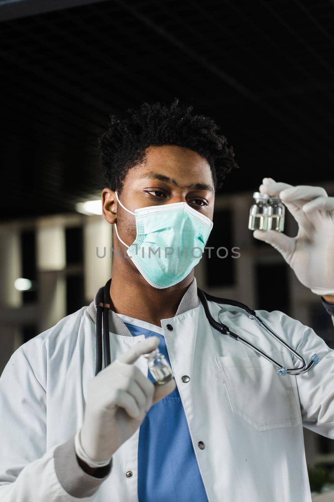 Black doctor with 3 doses of vaccine. Booster vaccination. African doctor in medical mask is holding vaccines in hand