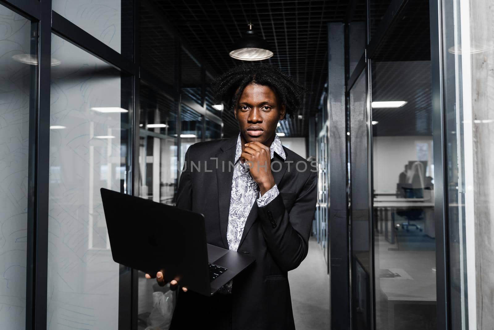 Confident black business man with laptop working online with his colleagues. Handsome african manager in the office